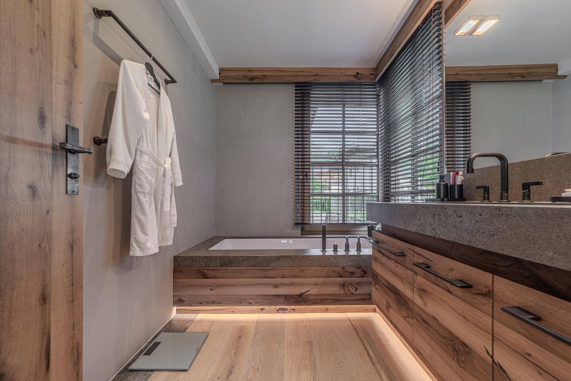 Modernes Badezimmer mit Holzelementen, eingebauter Badewanne und Doppelwaschbecken.