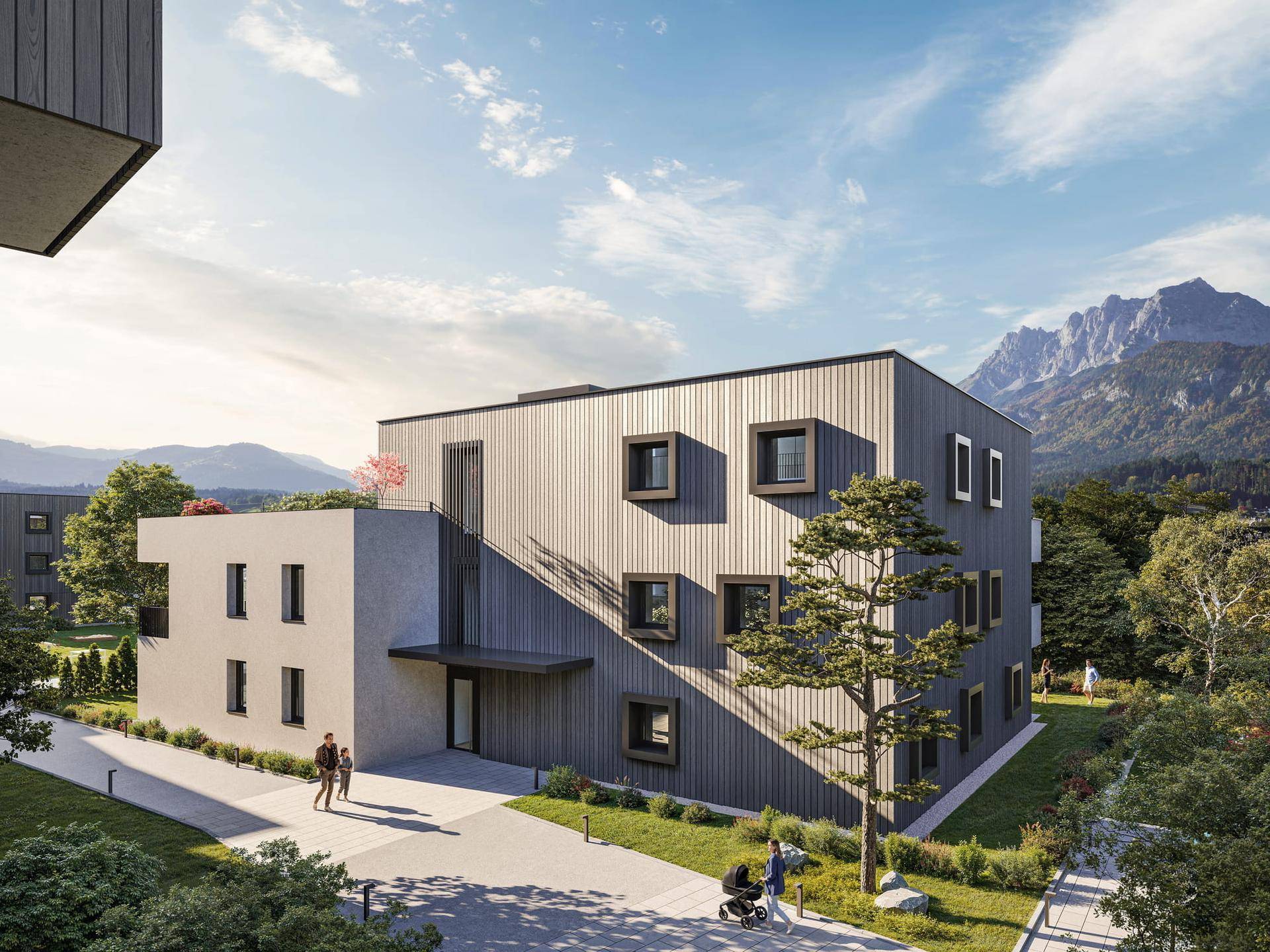 Moderne Wohnanlage mit markanter Fassade, umgeben von Natur und Bergblick.