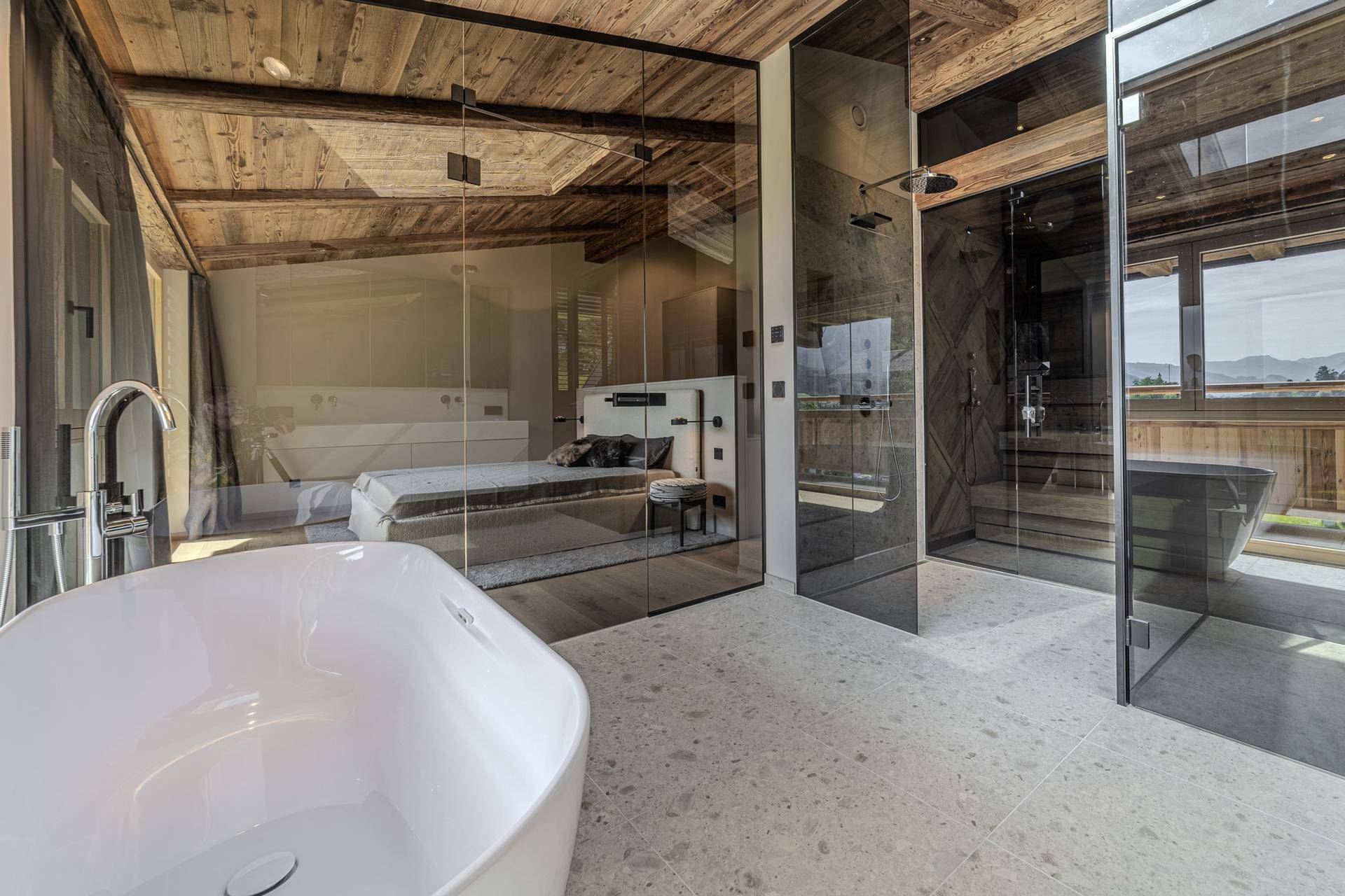 Luxuriöses Badezimmer mit freistehender Badewanne, Glasdusche und Blick auf das Schlafzimmer.