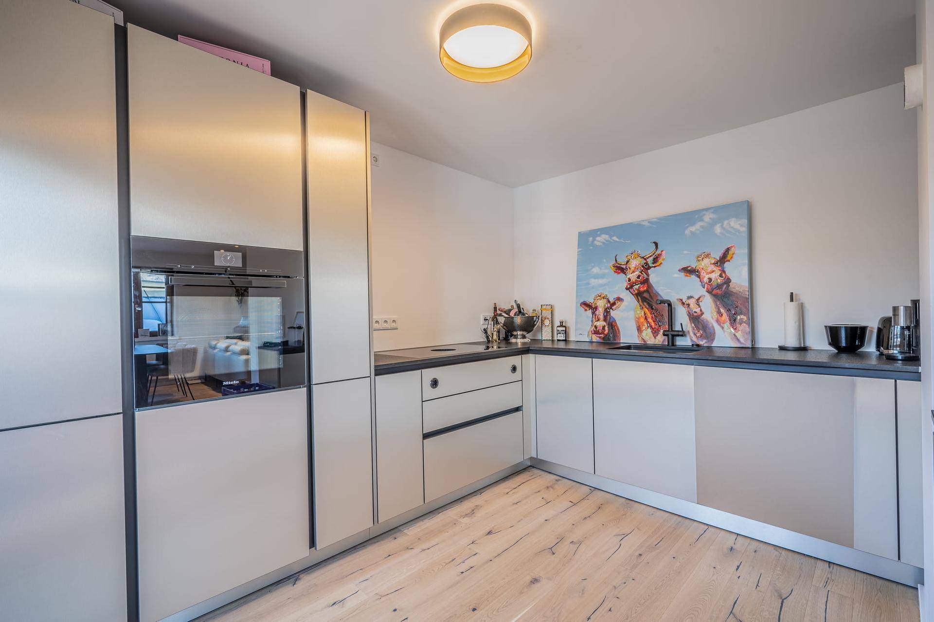 Moderne Küche mit hellen Schränken, integrierten Geräten, Holzboden und minimalistischem Design.