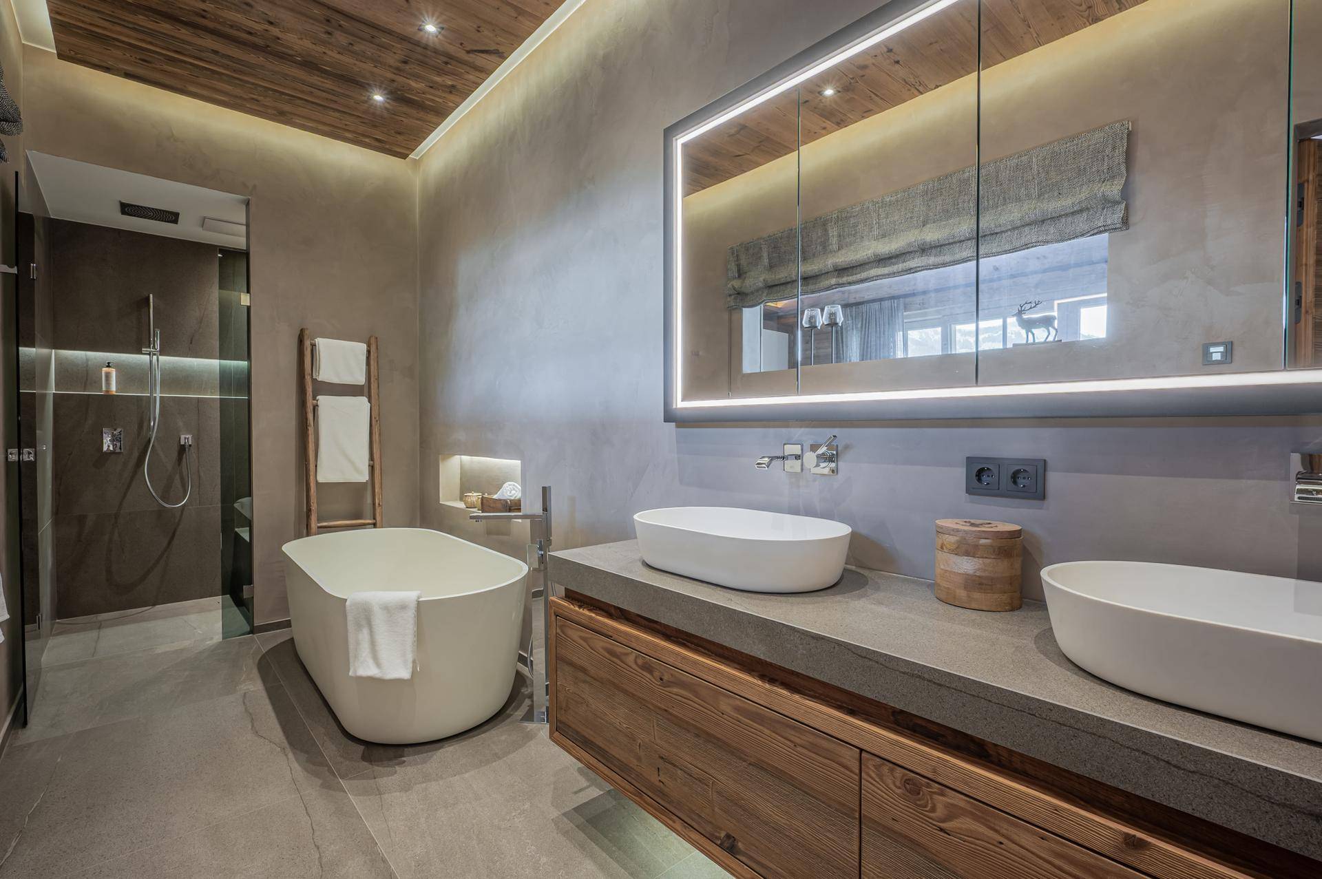 Elegantes Badezimmer mit freistehender Badewanne, Doppelwaschbecken und großer Spiegelschrankbeleuchtung.