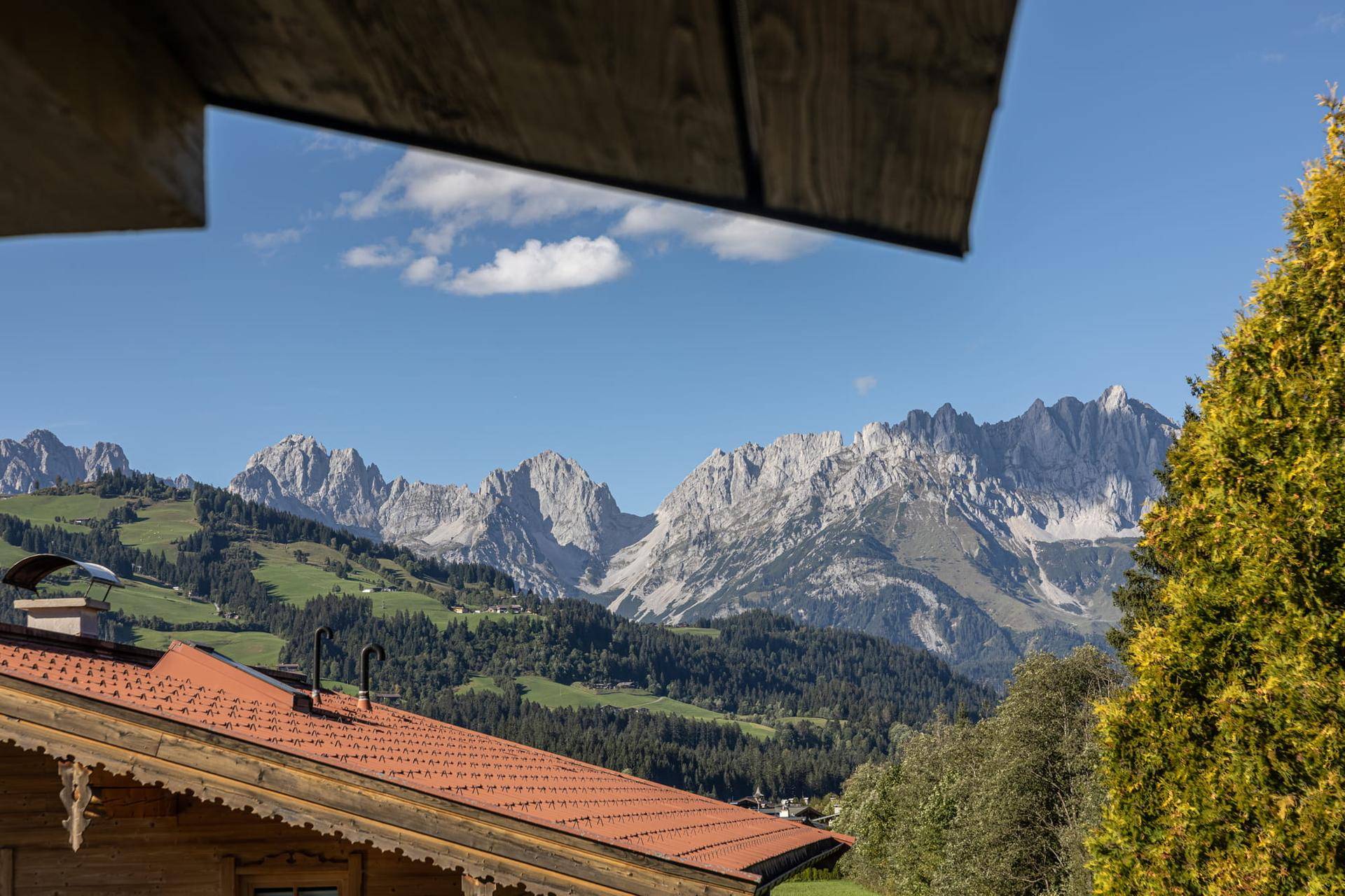 Atemberaubender Panoramablick auf die majestätischen Alpen und grüne Hügel unter blauem Himmel.