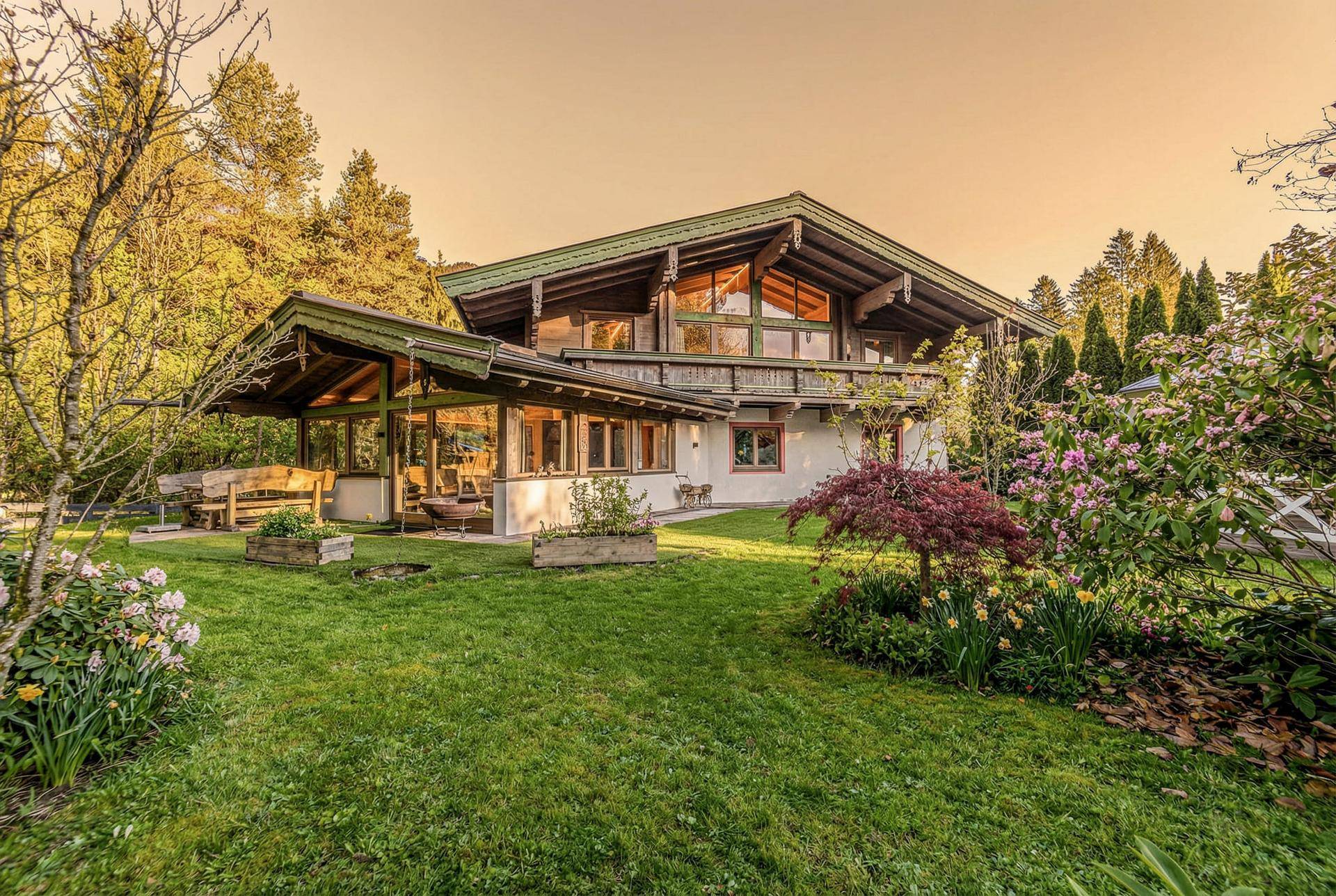 Idyllisches Chalet mit weitläufigem, gepflegtem Garten, blühenden Pflanzen und gemütlicher überdachter Veranda.