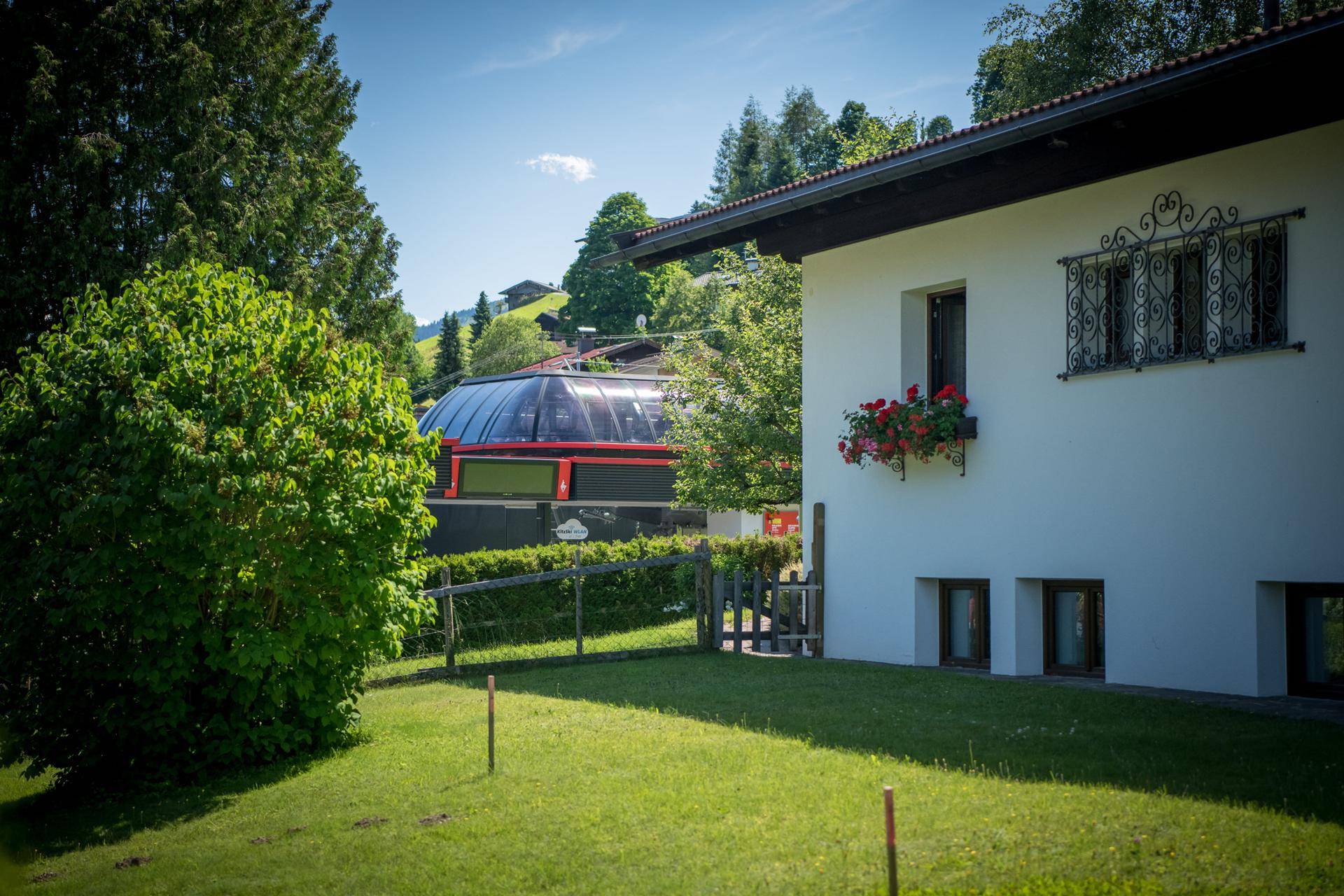 Seitenansicht des Hauses mit gepflegtem Rasen und Blick auf eine nahegelegene Gondelbahn.