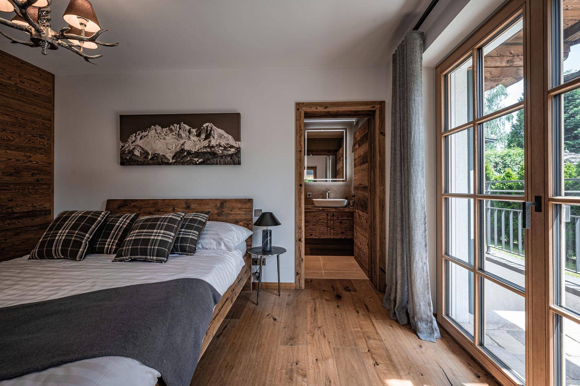 Gemütliches Schlafzimmer mit Holzboden und direktem Zugang zu einem eigenen Bad.