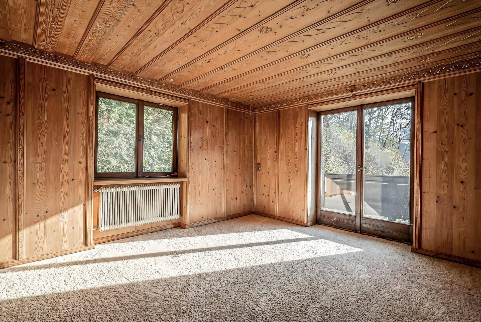 Gemütliches Schlafzimmer mit Holzvertäfelung, Teppichboden und direktem Zugang zum Balkon.