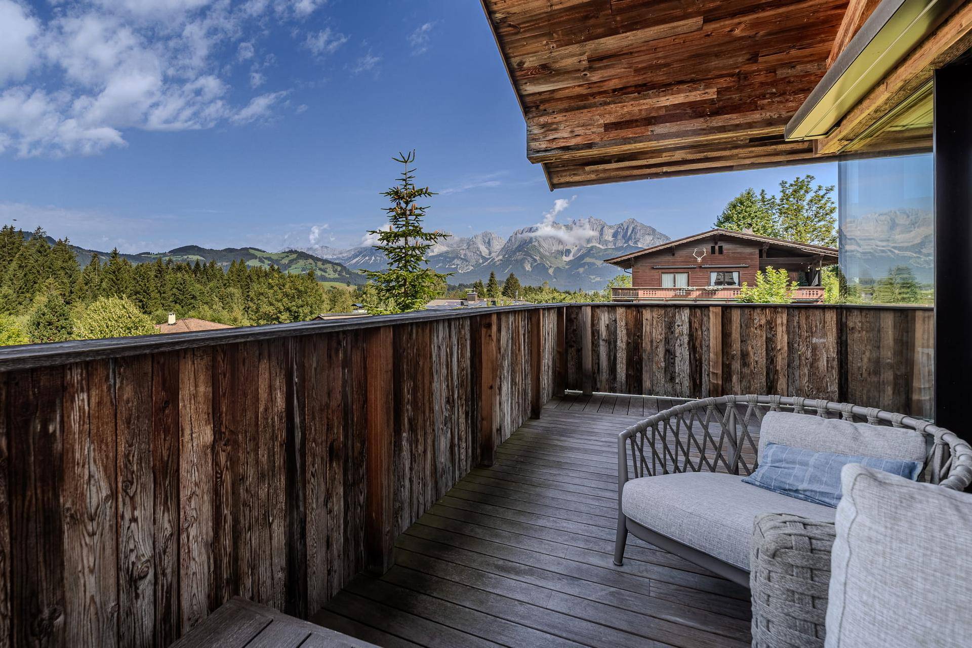 Gemütlicher Holzbalkon mit Sitzgelegenheiten und weitem Blick auf die umliegende Berglandschaft.