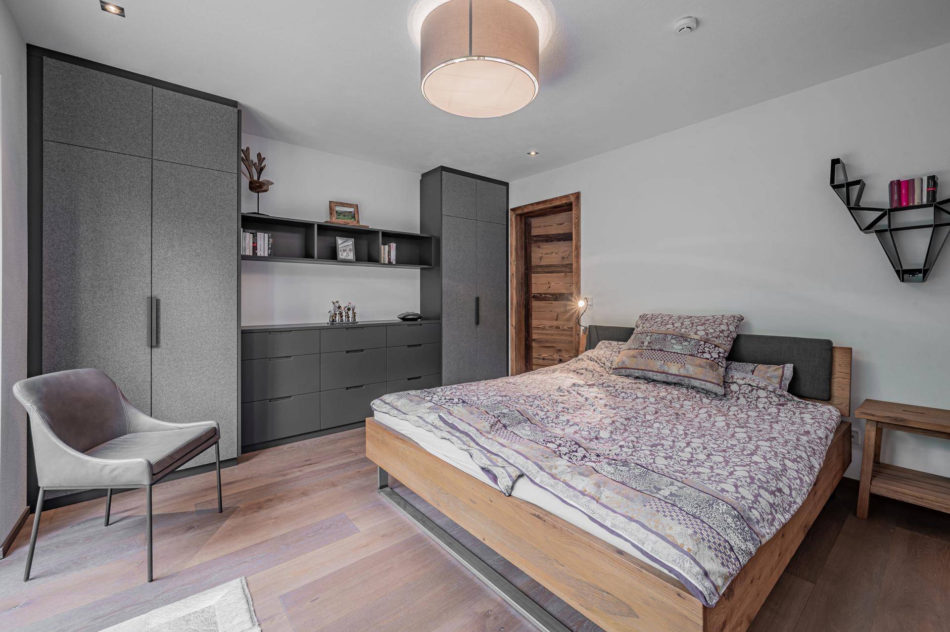 Modernes Schlafzimmer mit Holzbett, integrierten grauen Schränken und Holzboden.