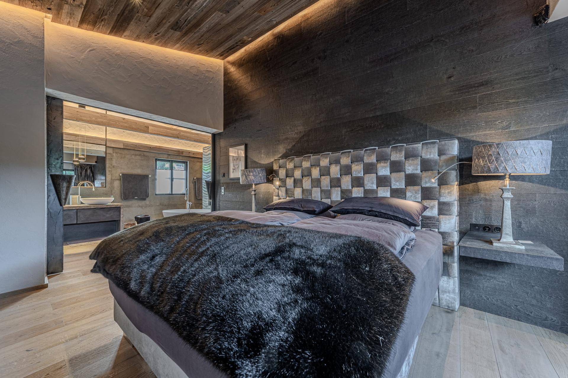 Modernes Schlafzimmer mit großem Bett, Holzboden und offenem Zugang zum luxuriösen Badezimmer.