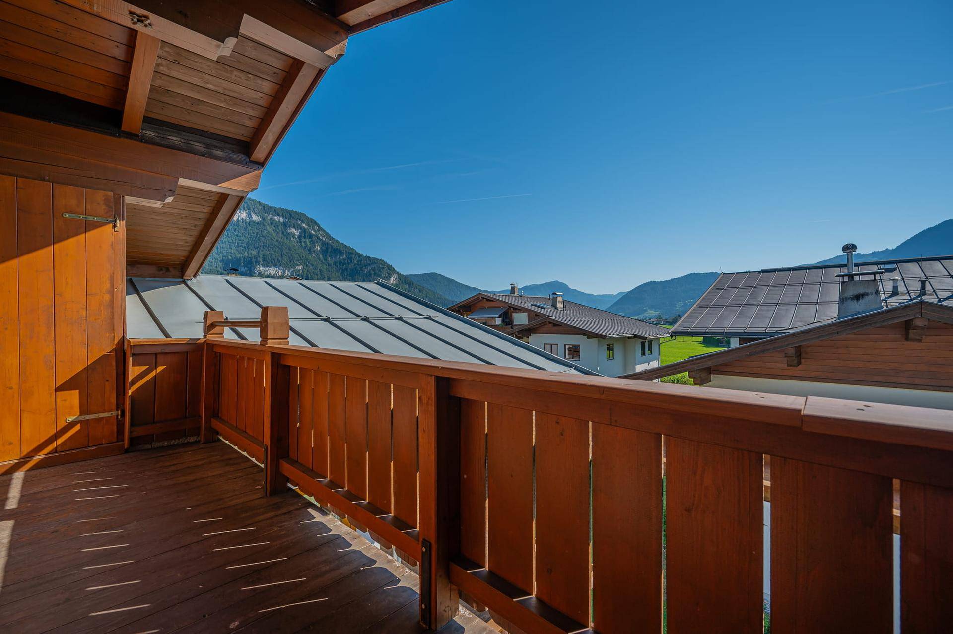 Geräumiger Holzbalkon mit traditionellem Geländer und weitem Blick auf die Berge.