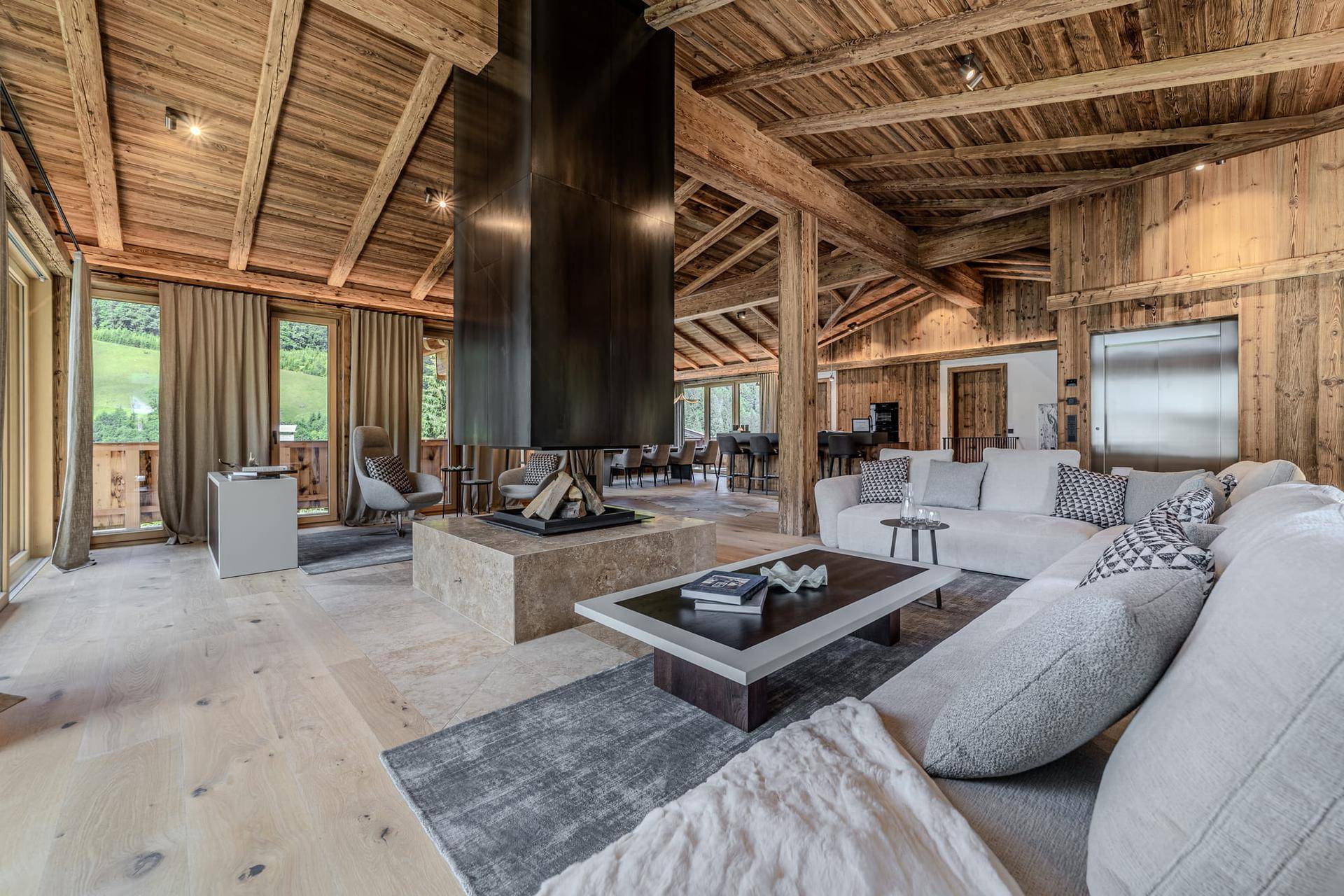 Geräumiges Wohnzimmer im alpinen Stil mit Holzbalken, modernem Kamin und gemütlicher Sitzecke.