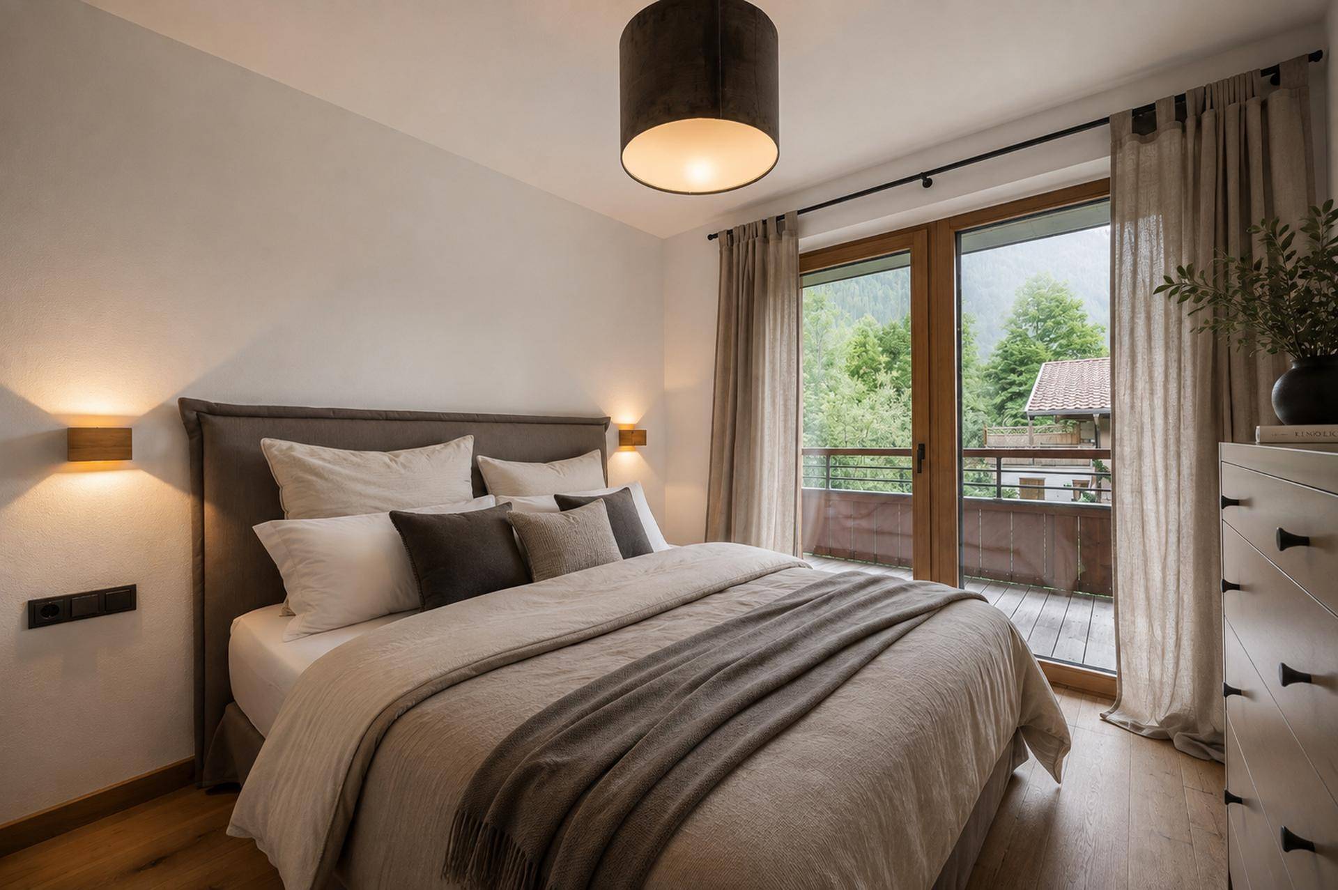 Helles Schlafzimmer mit Doppelbett, Holzboden und direktem Zugang zu einem Balkon mit Bergblick.