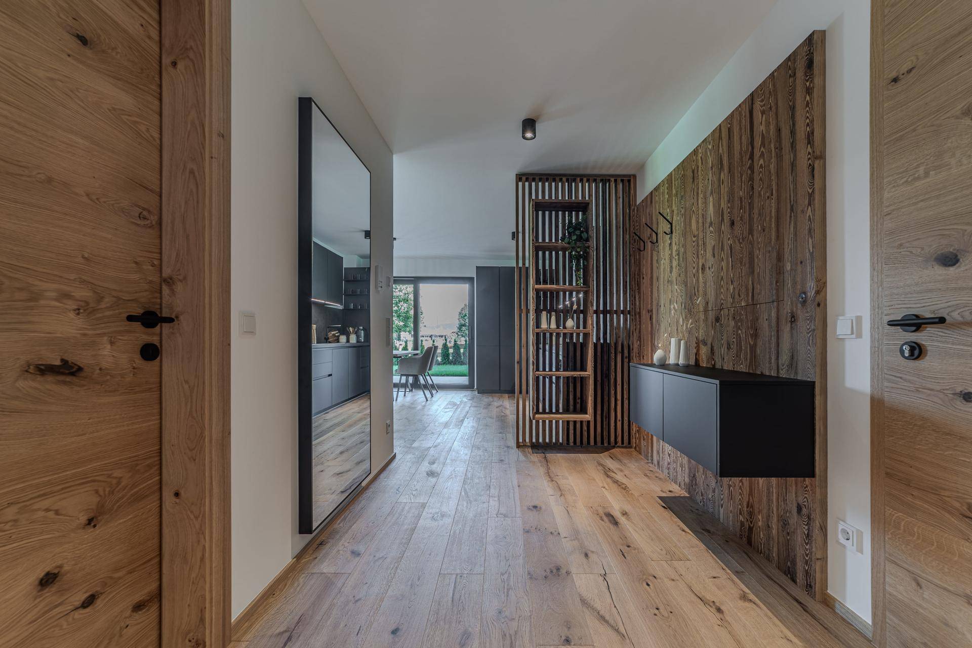 Heller Flur mit Holzwänden, einem großen Spiegel und modernen Holztüren, die den Eingangsbereich prägen.