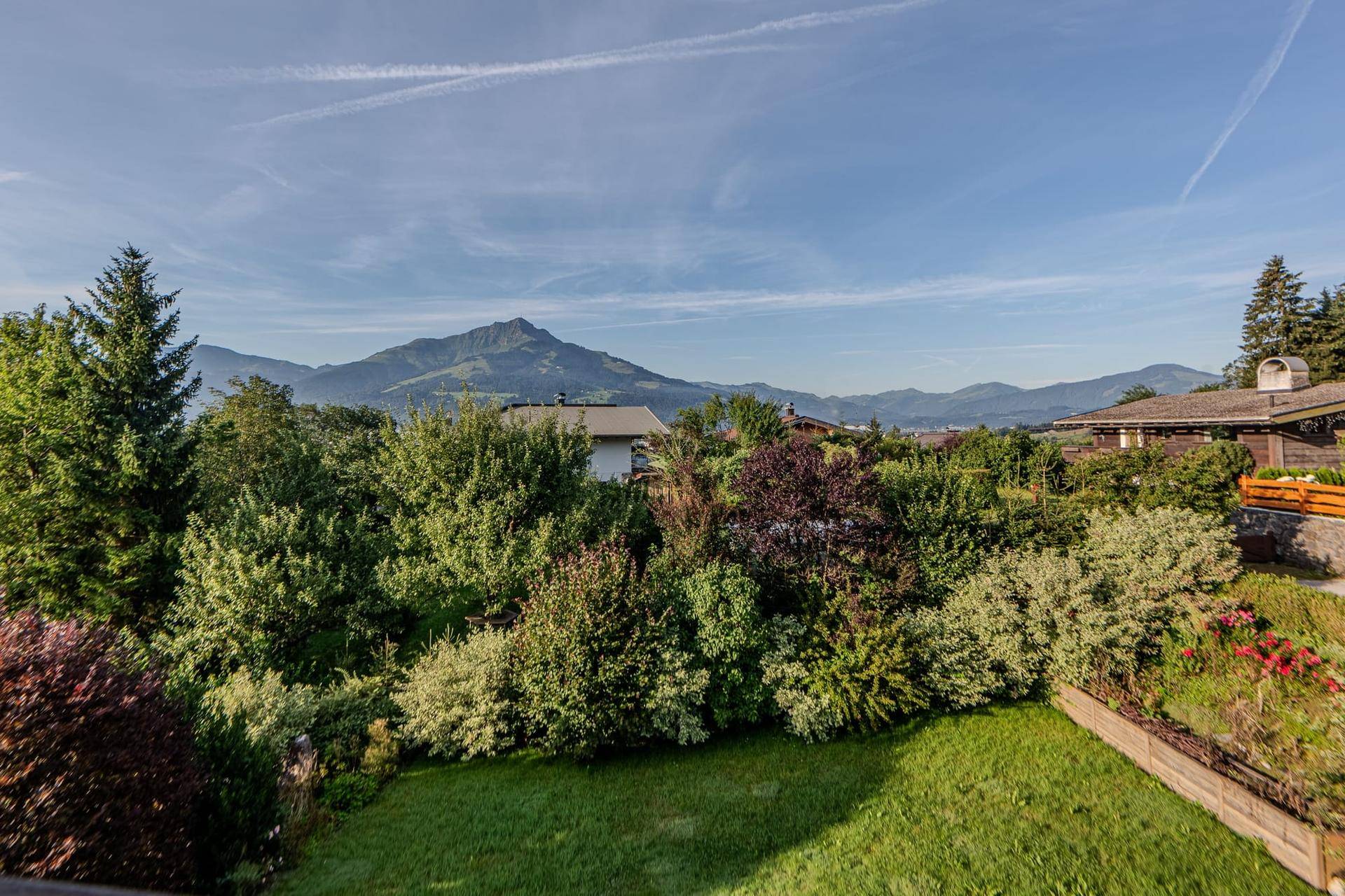 Gepflegter Gartenbereich mit vielfältiger Bepflanzung und weitem Blick auf die Berge.