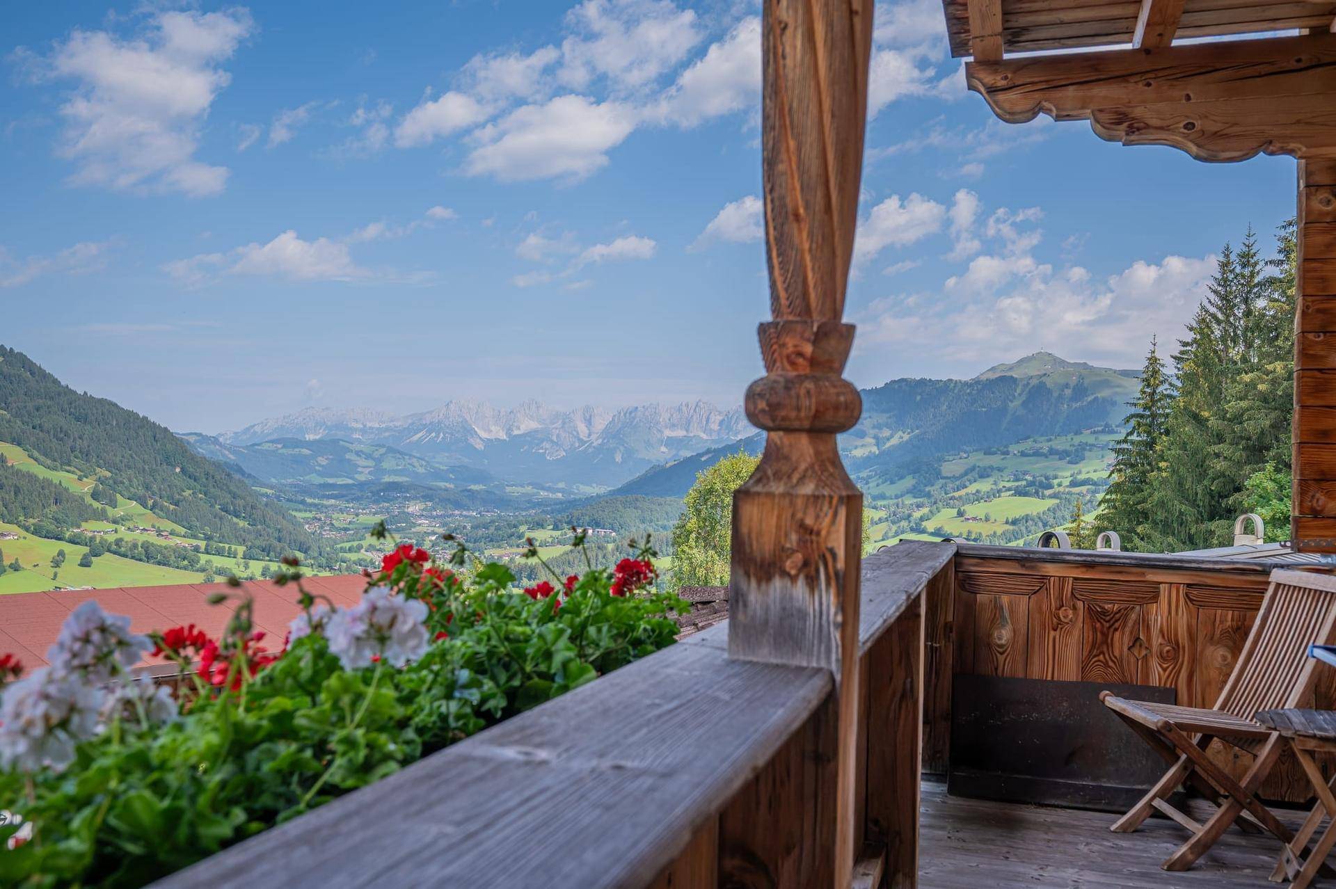 Gemütlicher Balkon mit Holzelementen, Blumenkästen und weitem Bergblick in die Alpen.