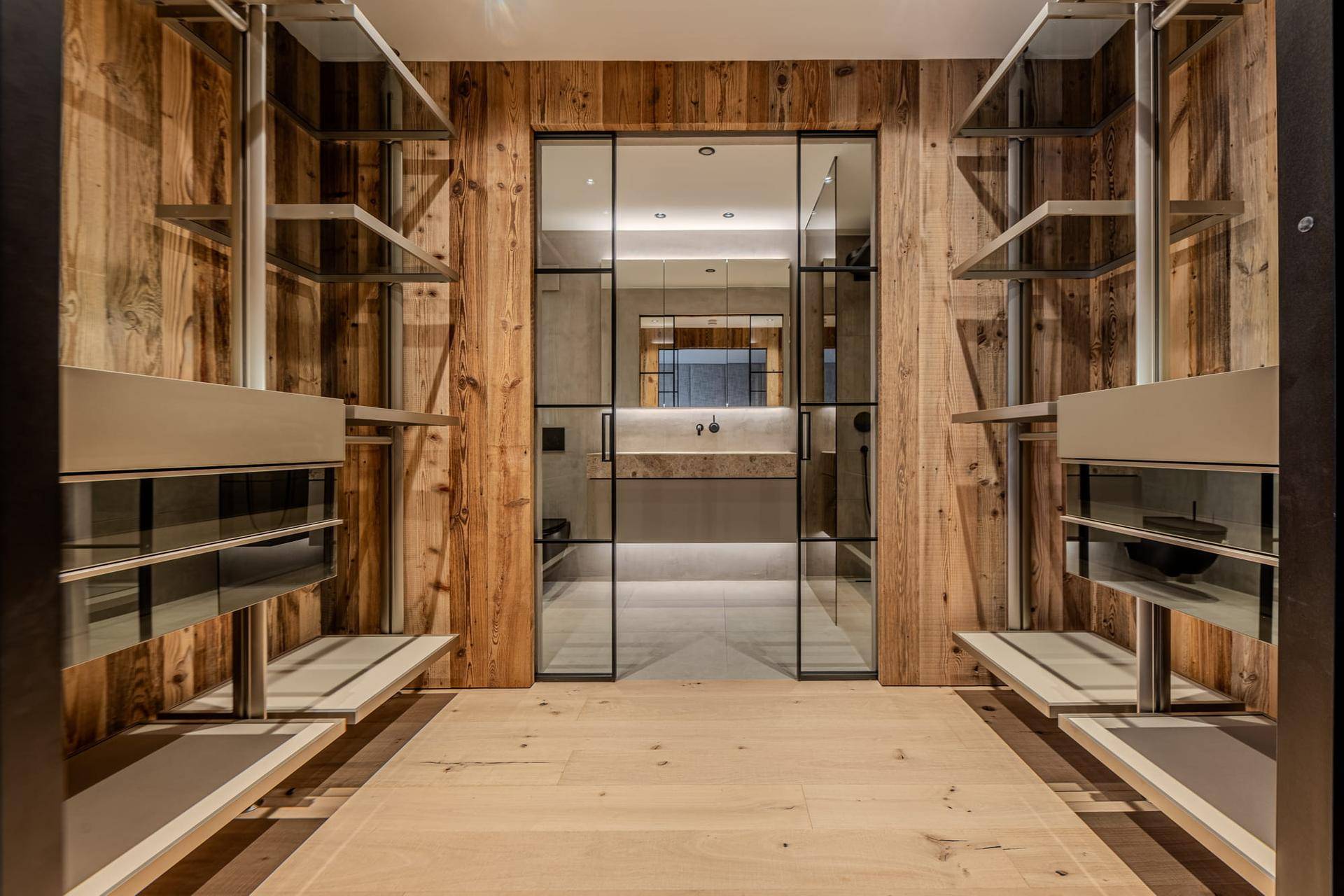 Geräumiger Ankleidebereich mit Holzwänden und Zugang zu einem modernen Badezimmer.