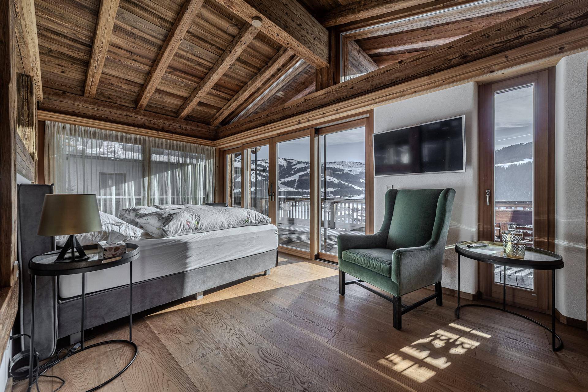Gemütliches Schlafzimmer mit Holzelementen, großem Bett und Panoramafenstern mit Bergblick.