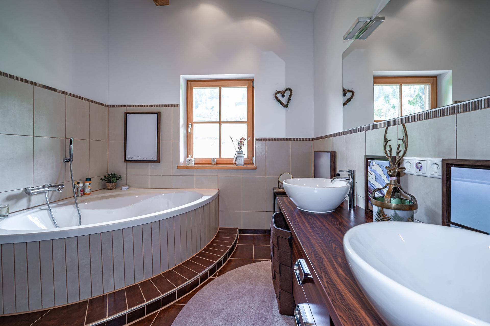 Geräumiges Badezimmer mit Eckbadewanne, Doppelwaschbecken und Fenster für Tageslicht.