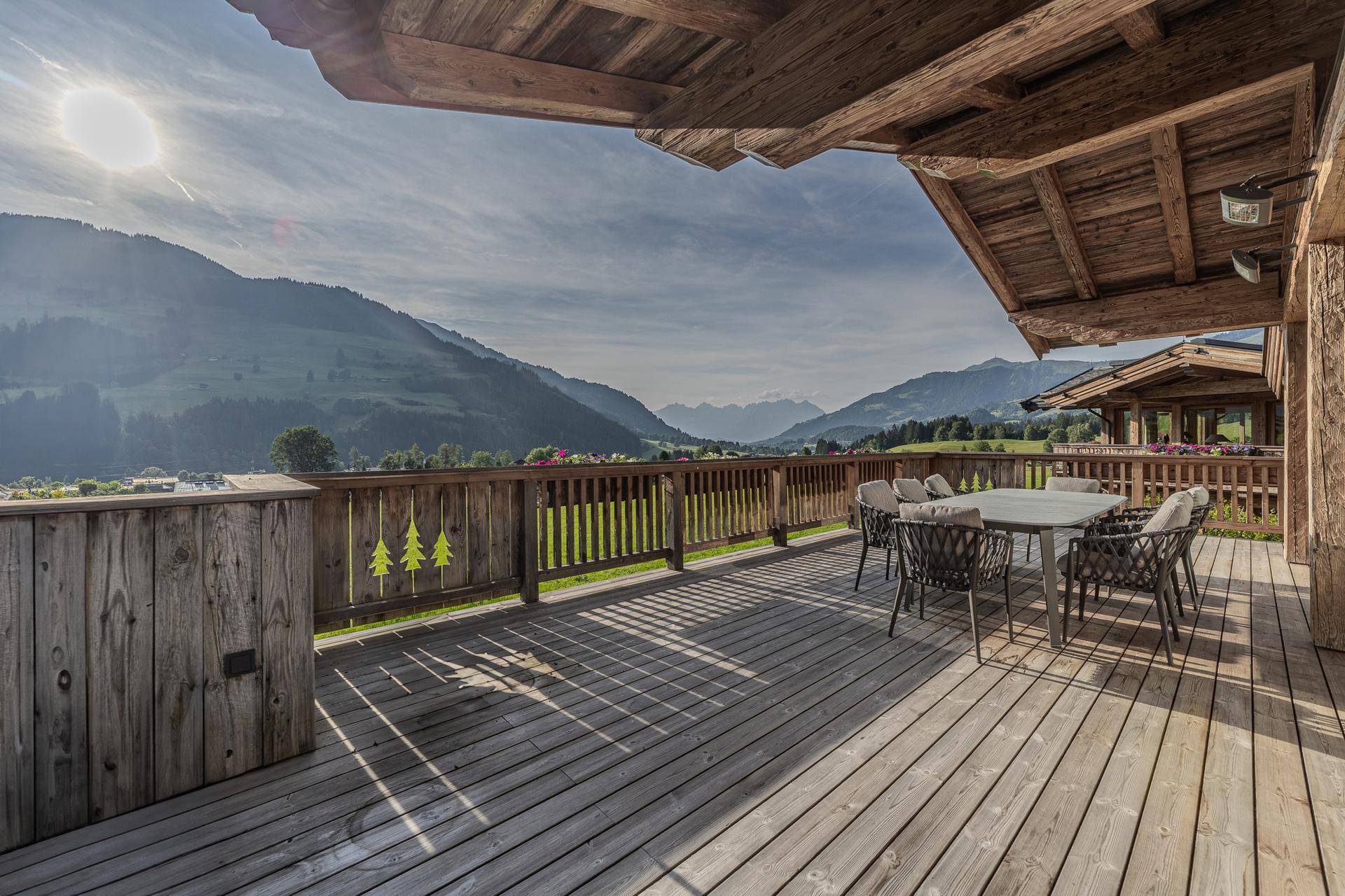 Große Holzterrasse mit Esstisch und atemberaubendem Blick auf die umliegende Berglandschaft.
