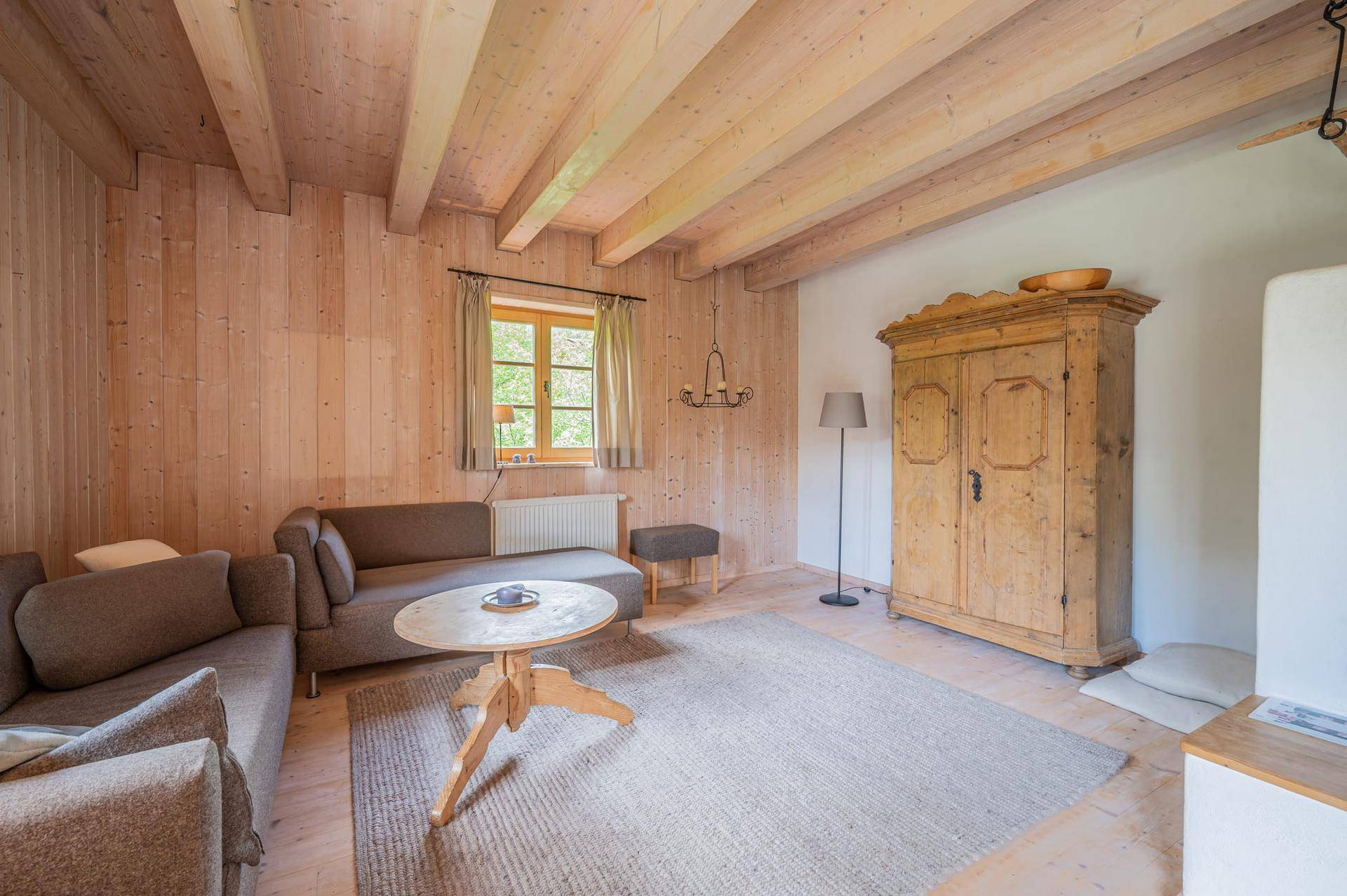 Gemütliches Wohnzimmer mit Holzwänden, sichtbaren Deckenbalken und traditionellen Möbeln.