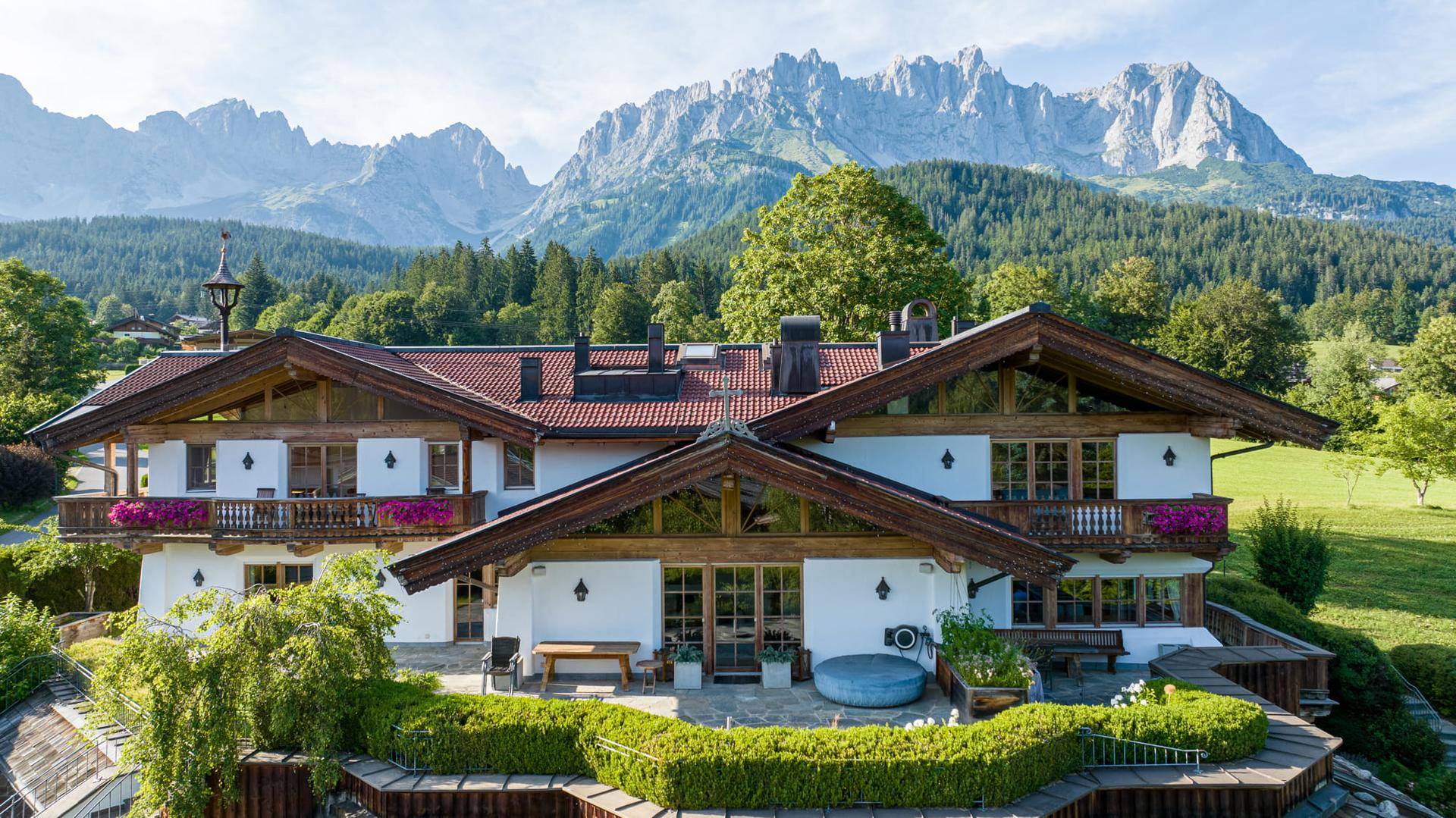 Charmantes Alpenhaus mit großer Terrasse, Whirlpool und beeindruckendem Bergblick im Hintergrund.