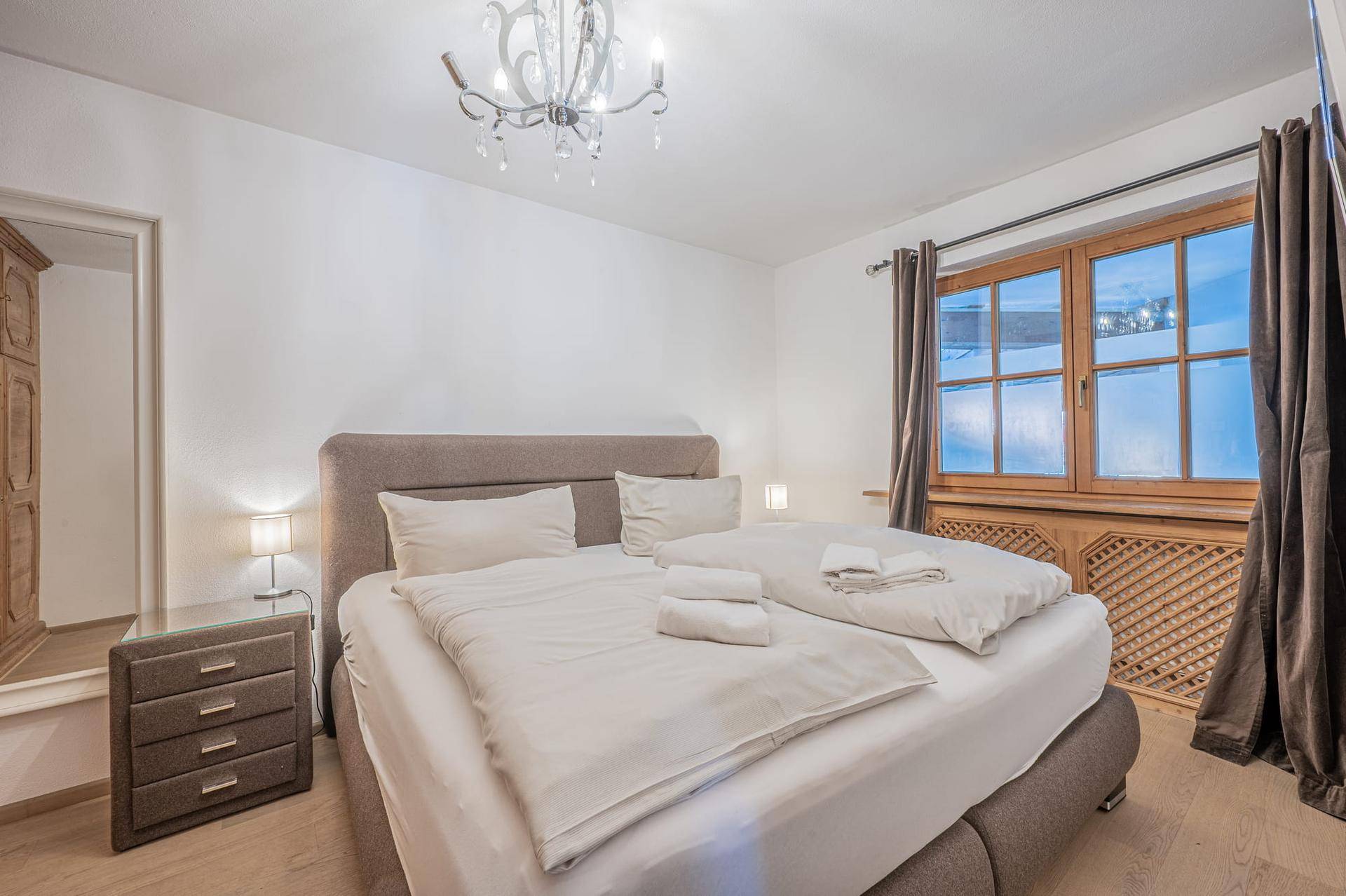Gemütliches Schlafzimmer mit Doppelbett, Holzboden und Blick auf eine verschneite Landschaft.