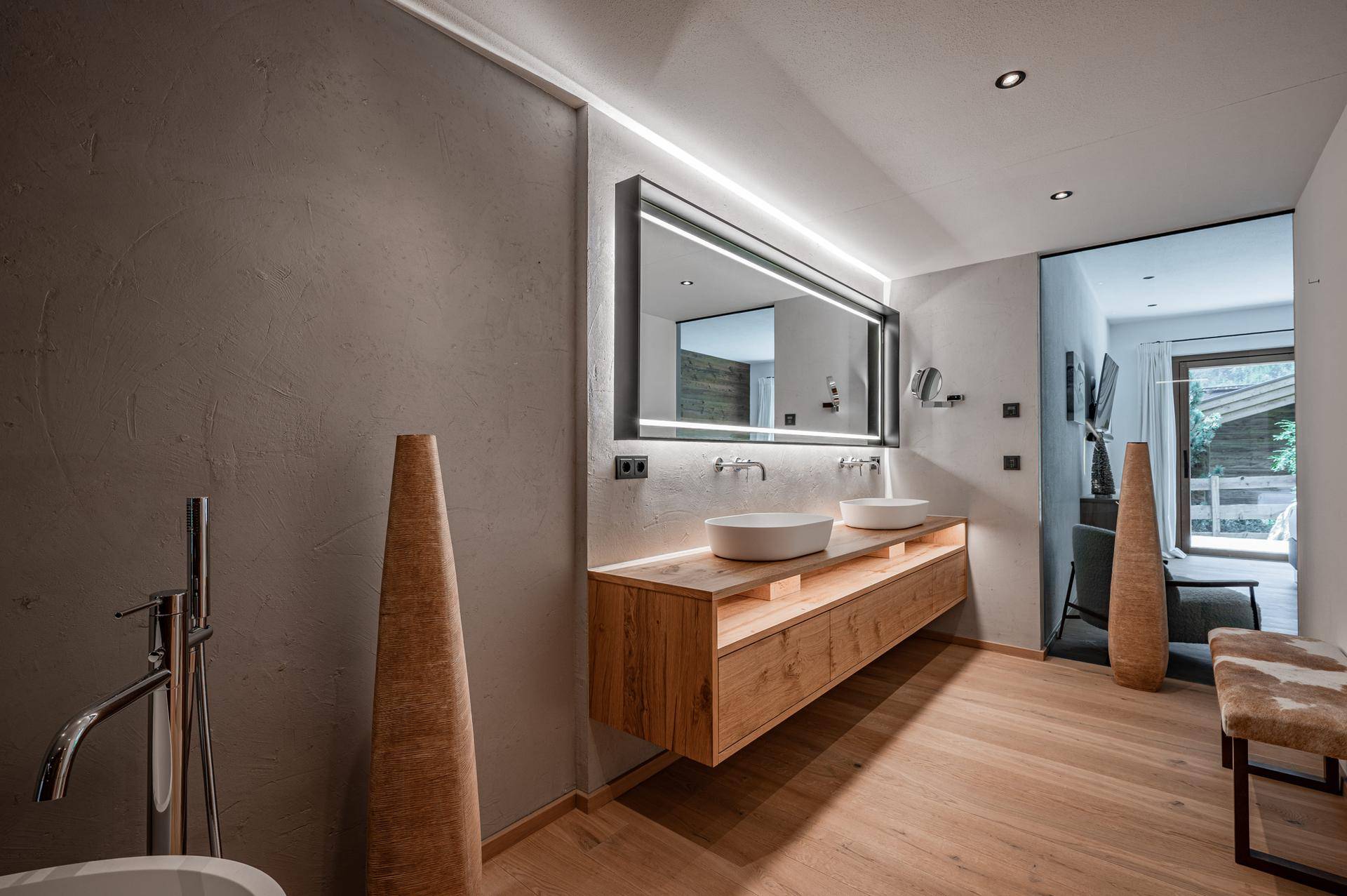 Elegantes Badezimmer mit Doppelwaschbecken, beleuchtetem Spiegel und Holzfußboden.