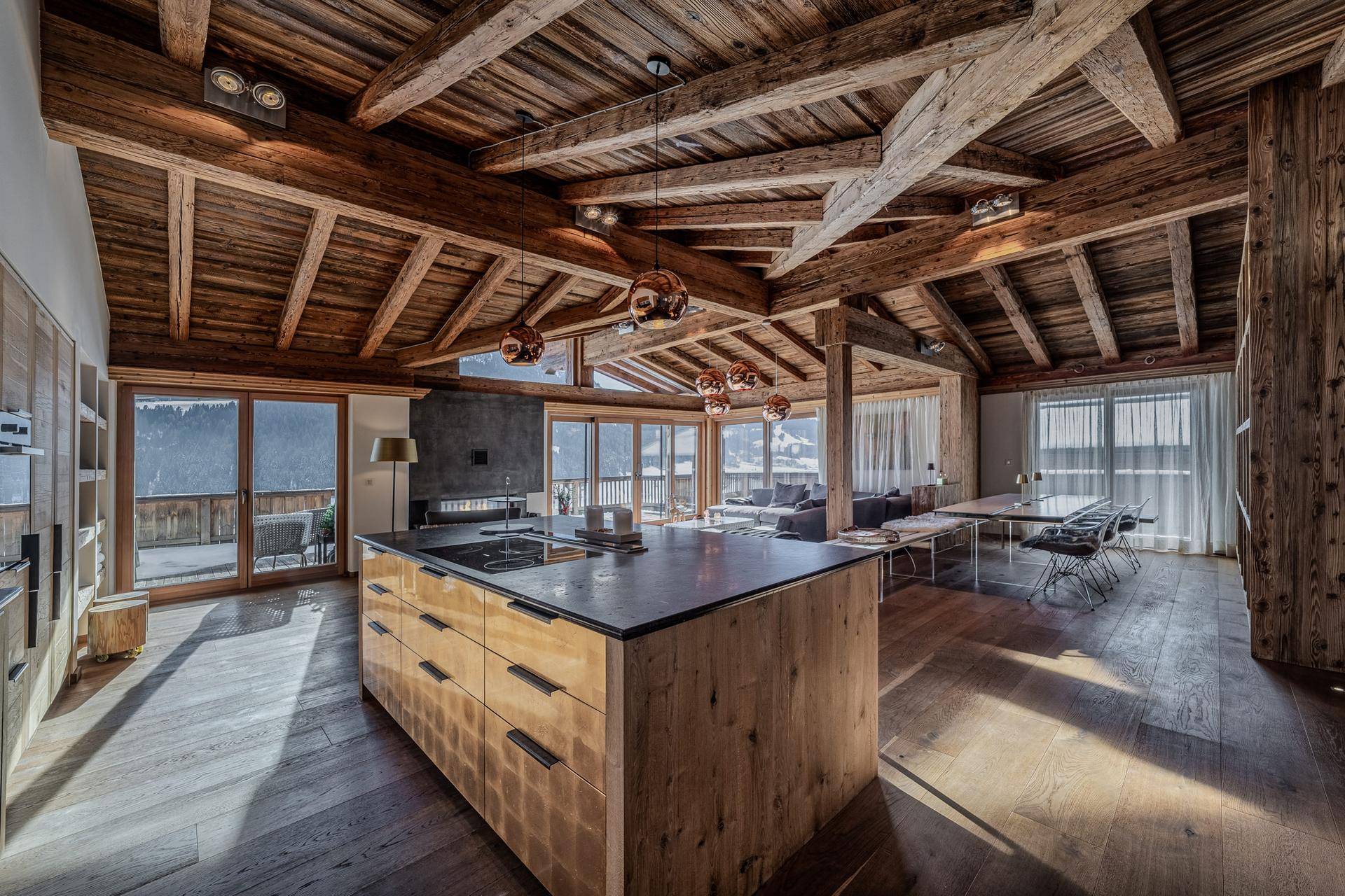 Moderne Küche mit Kochinsel und Essbereich, offen zum Wohnzimmer mit Bergblick.