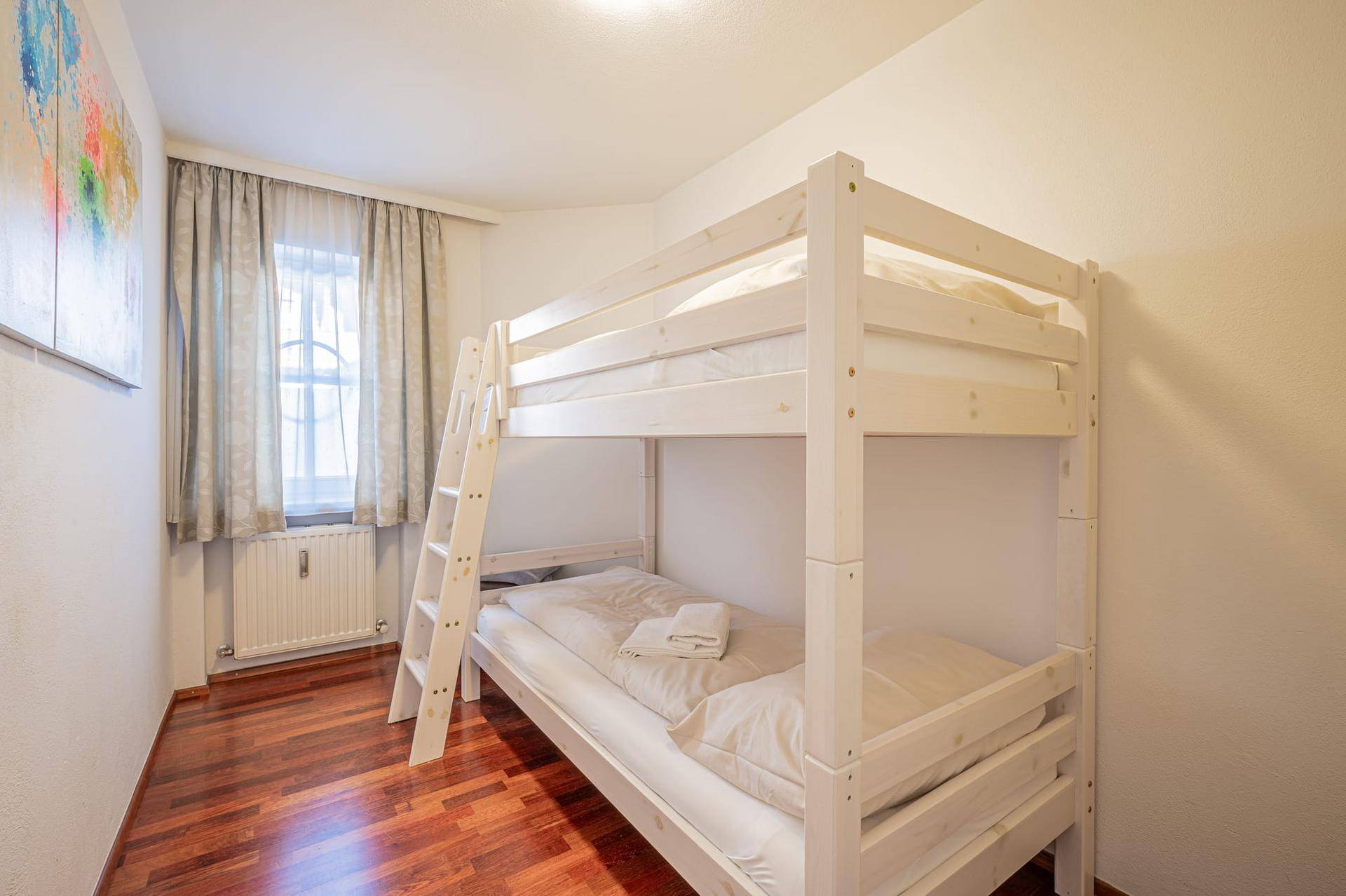 Kinderzimmer mit Etagenbett, Holzboden und hellem Fenster, ideal für Geschwister oder Gäste.