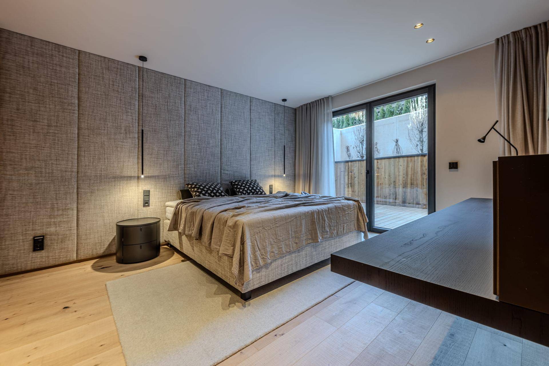 Modernes Schlafzimmer mit großem Bett, Holzboden und direktem Zugang zur Terrasse.