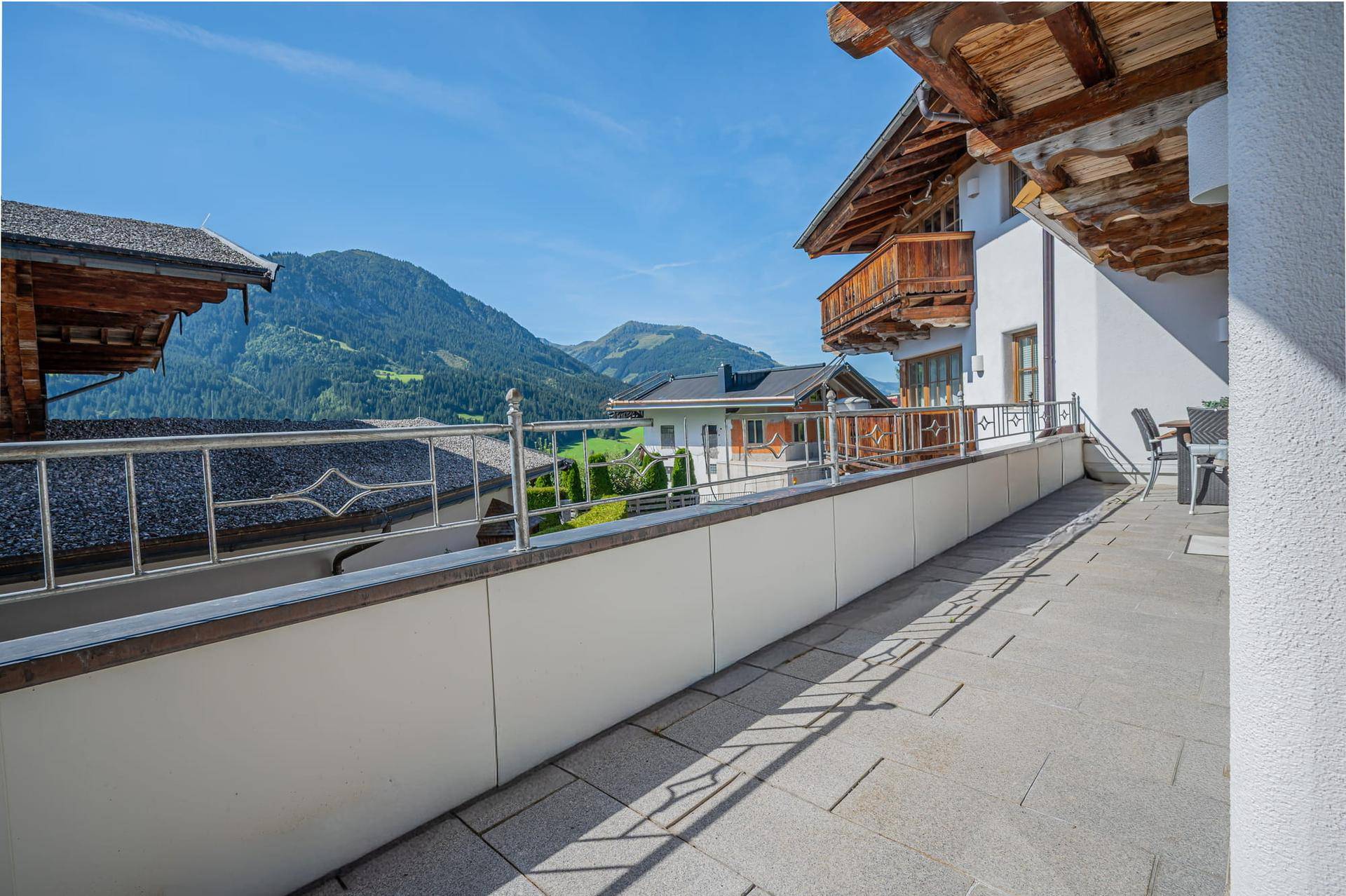 Großer Balkon mit Panoramablick auf die umliegende Bergwelt und traditioneller Architektur.