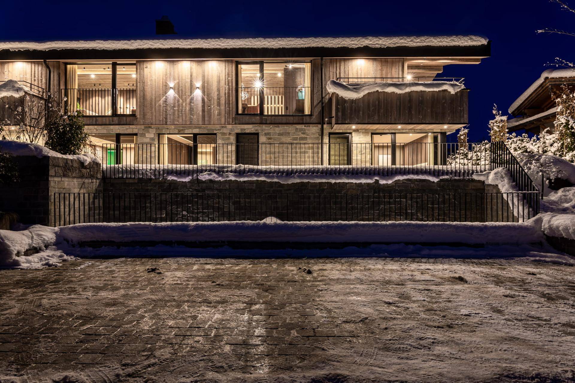Beeindruckende Außenansicht des Gebäudes bei Nacht im Winter, beleuchtet und schneebedeckt.