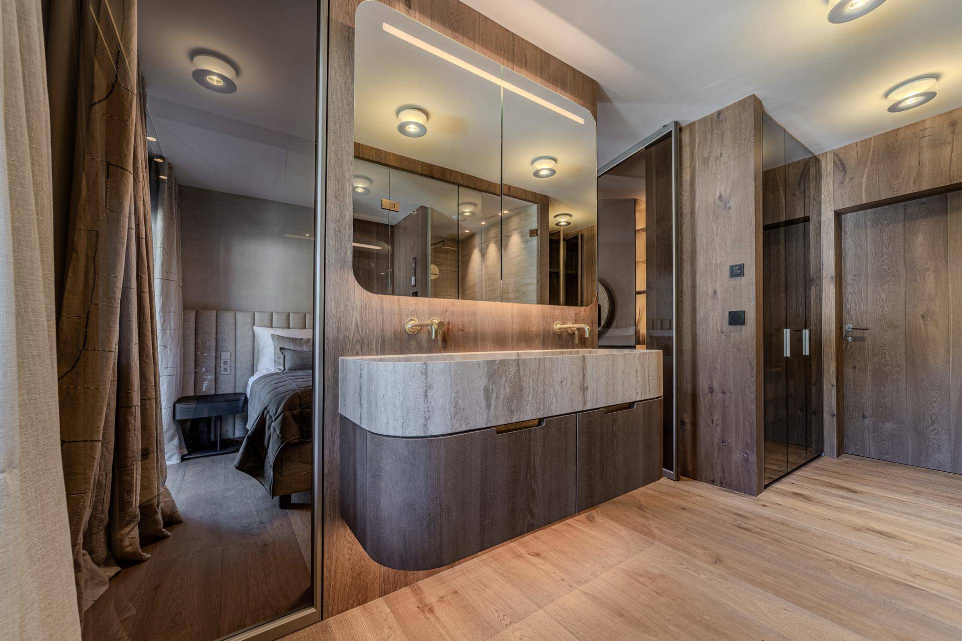 Exklusives Badezimmer mit Doppelwaschbecken, integrierten Schränken und Blick ins Schlafzimmer.