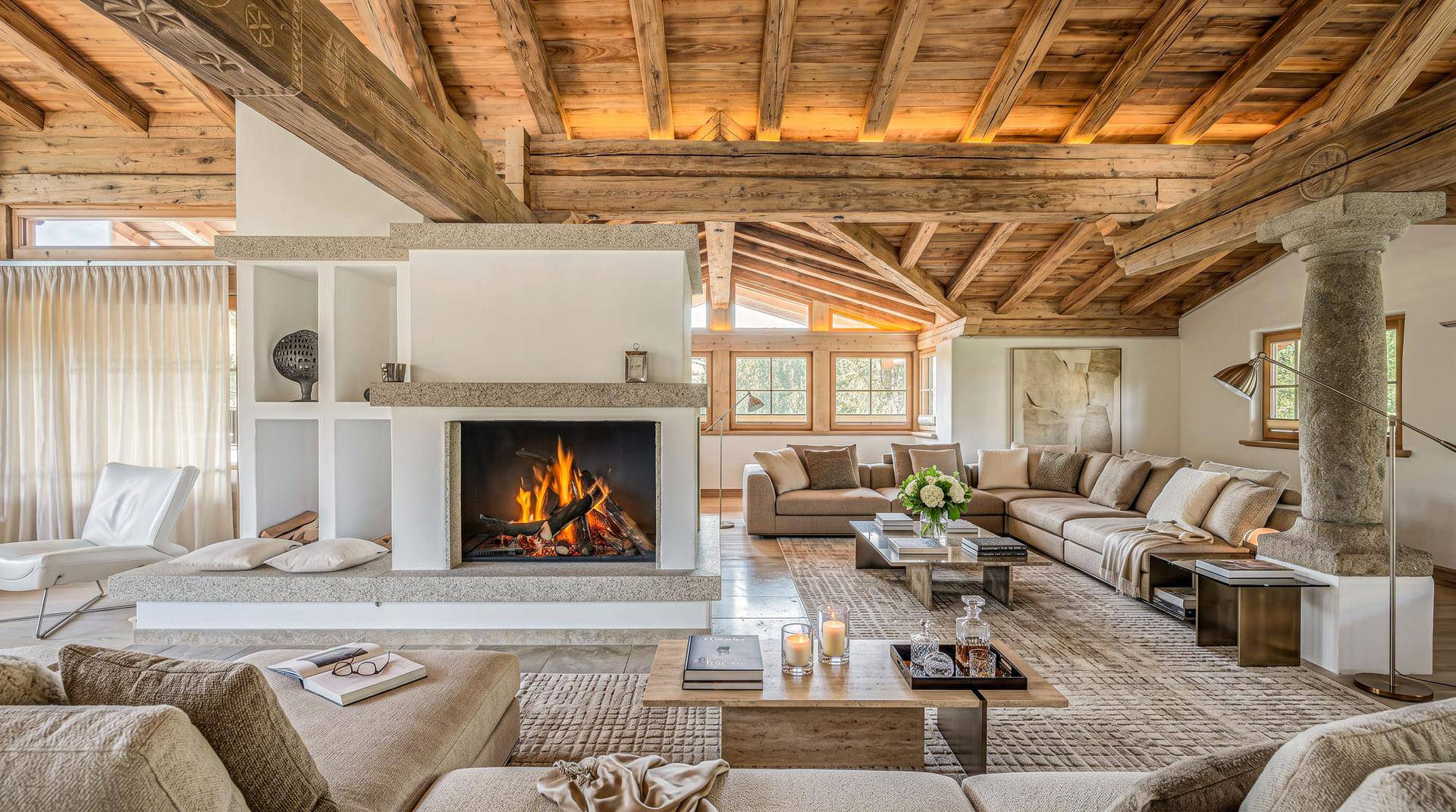 Großzügiges Wohnzimmer mit imposantem Kamin, sichtbaren Holzbalken und hellen, modernen Möbeln.