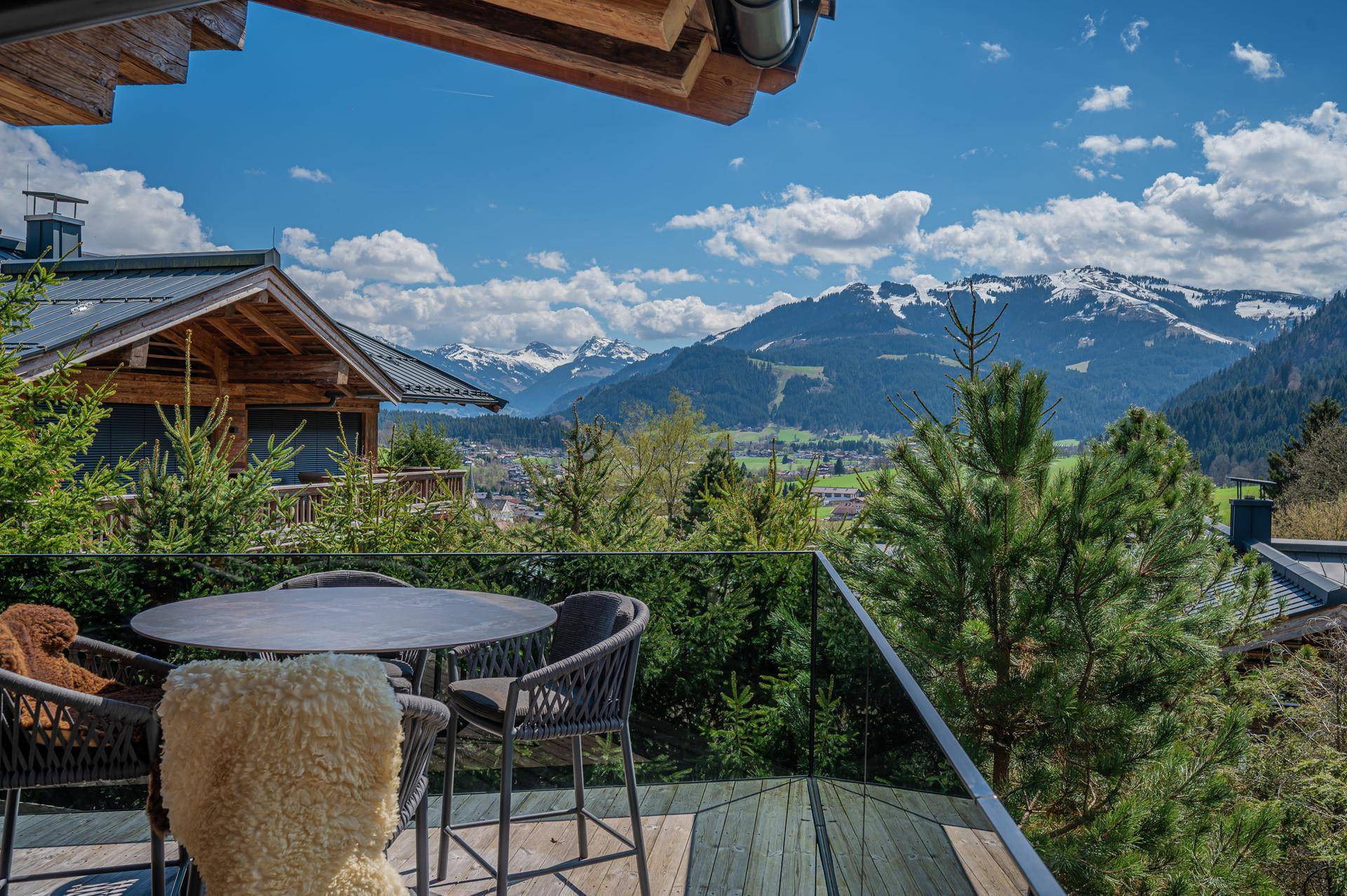 Sonniger Balkon mit Sitzgelegenheiten und atemberaubendem Blick auf die umliegende Berglandschaft.