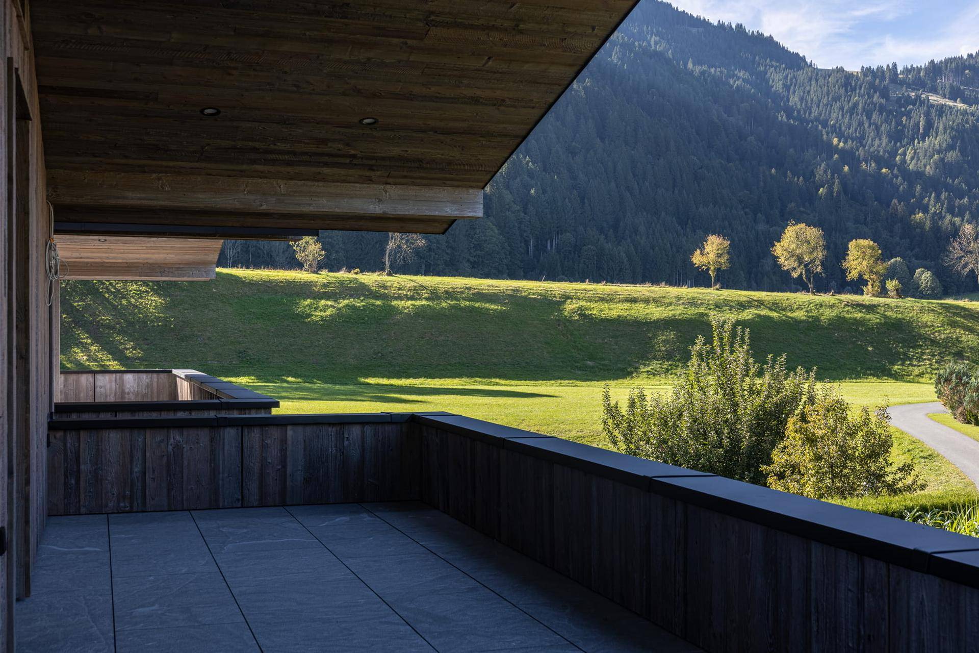 Geräumige Terrasse mit Holzelementen und weitem Blick auf die grüne Hügellandschaft.