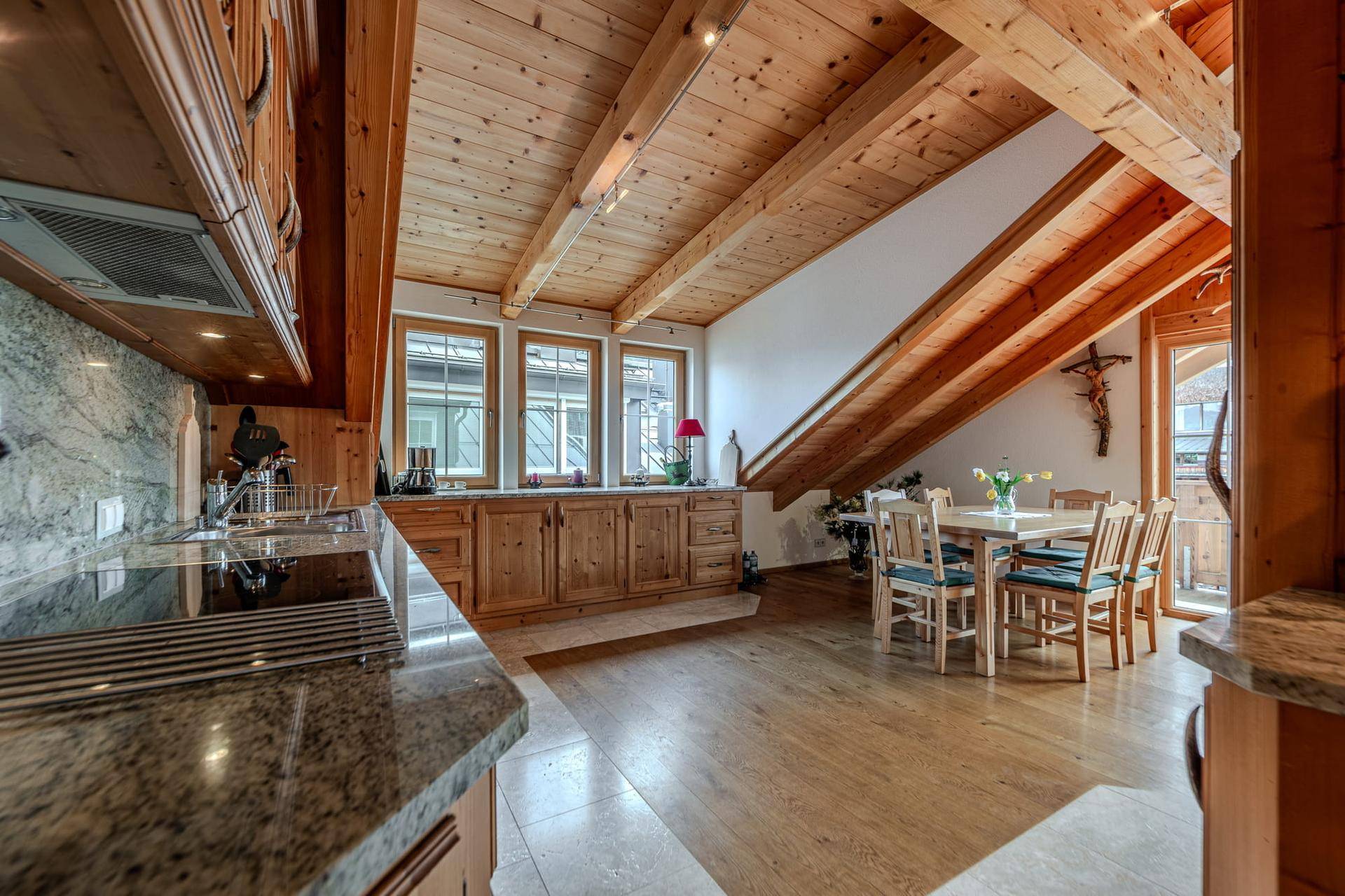 Offene Küche mit Holzeinbauten, Granitarbeitsplatten und angrenzendem Essbereich mit Holztisch.