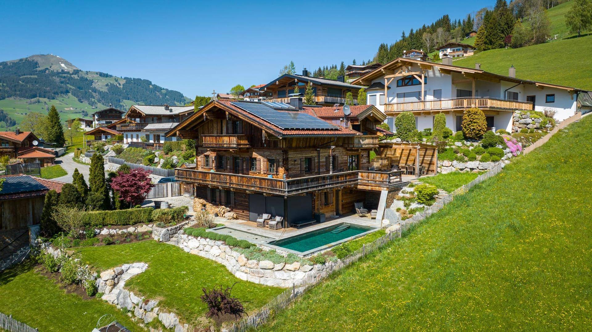 Exklusives Holzchalet mit Pool in Hanglage und Panoramablick auf die umliegende Alpenlandschaft.