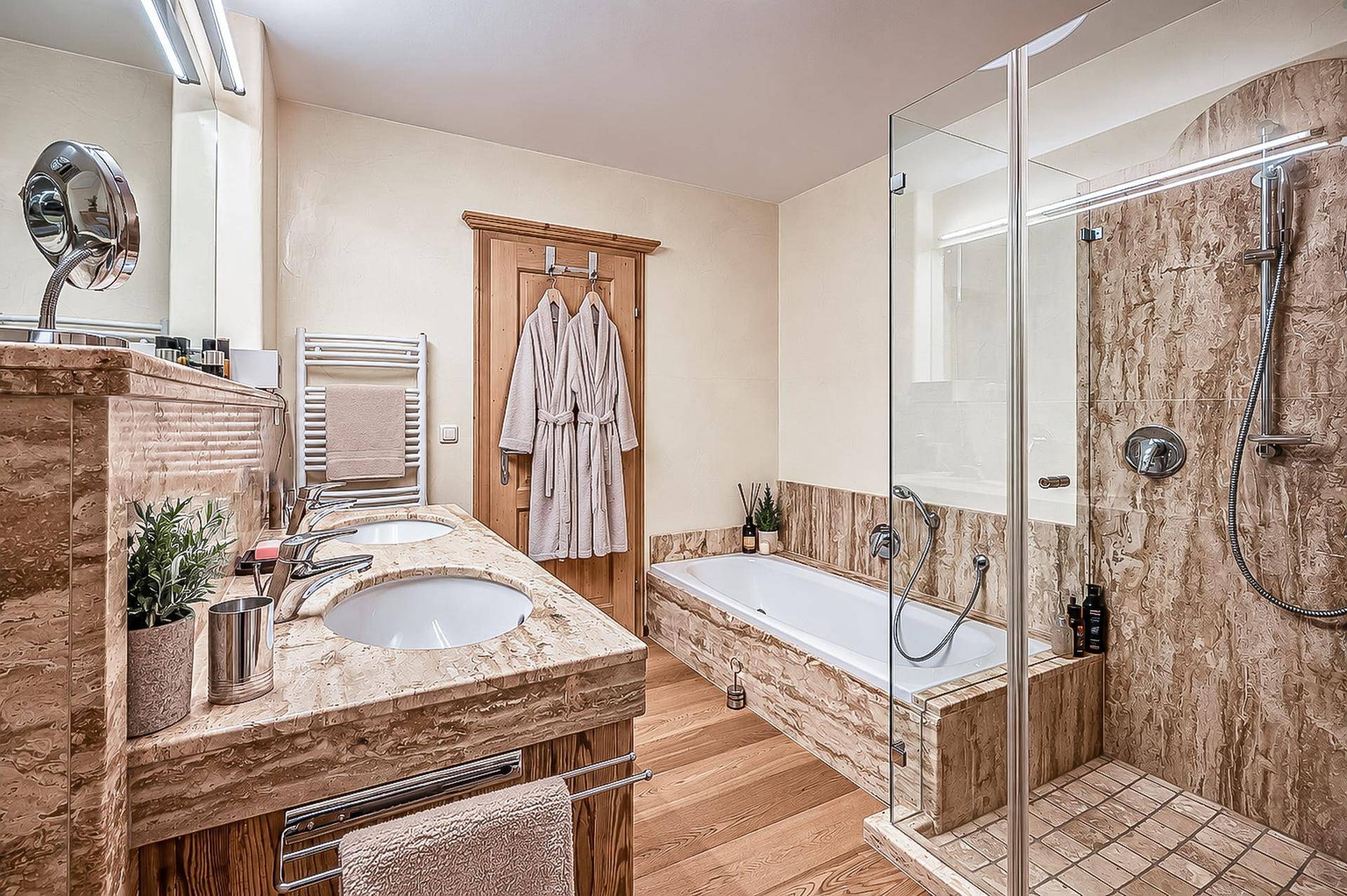 Luxuriöses Badezimmer mit Doppelwaschbecken, Badewanne und begehbarer Dusche in Marmoroptik.
