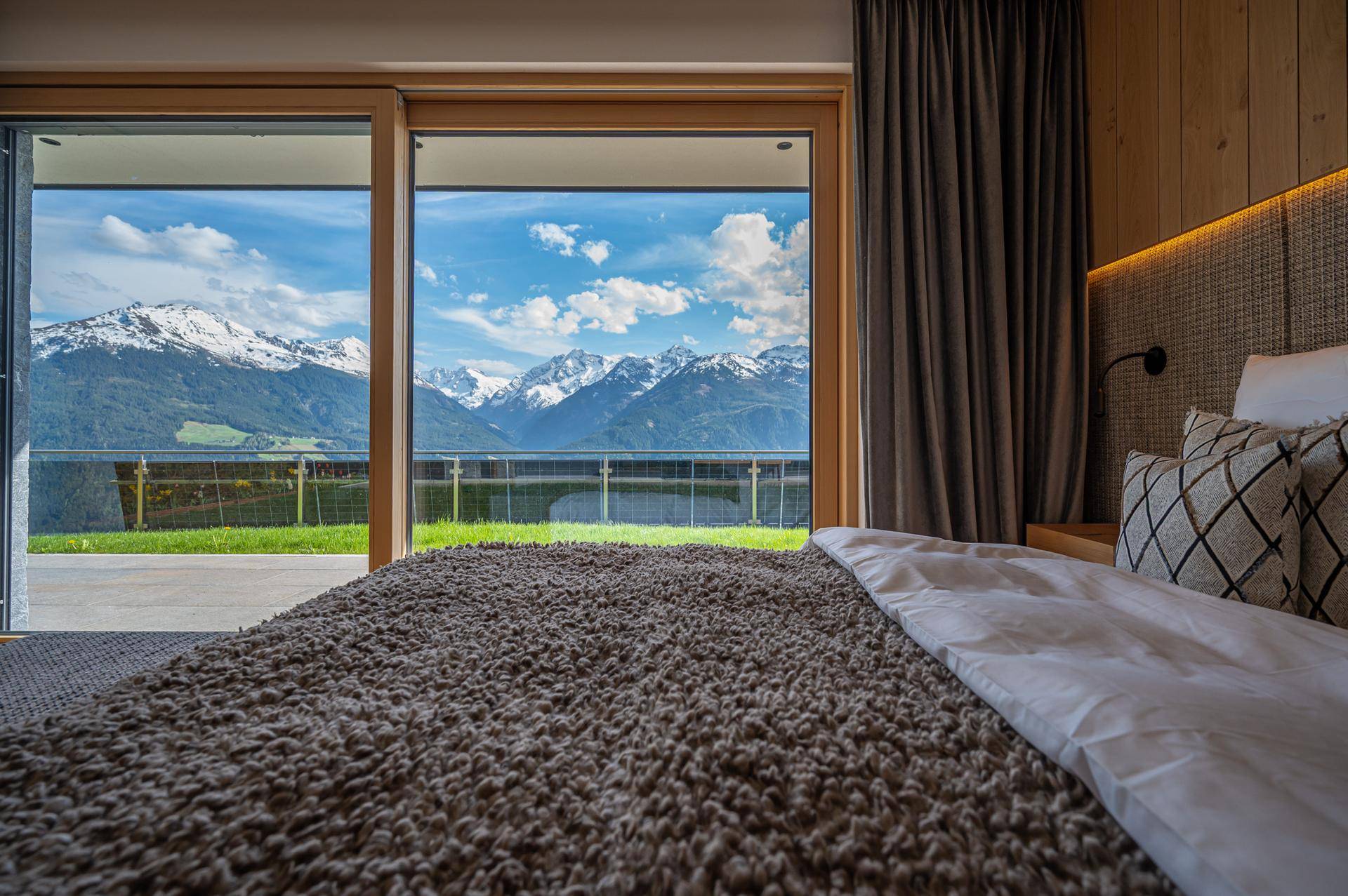 Gemütliches Schlafzimmer mit großen Schiebetüren, die einen direkten Blick auf die majestätischen Berge bieten.