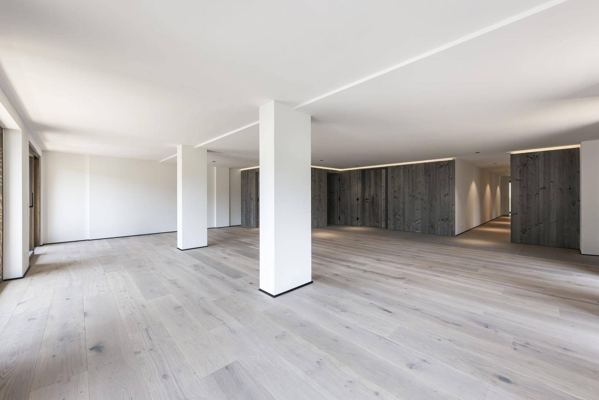 Moderner, offener Wohnbereich mit Holzboden und Akzentwänden aus dunklem Holz.