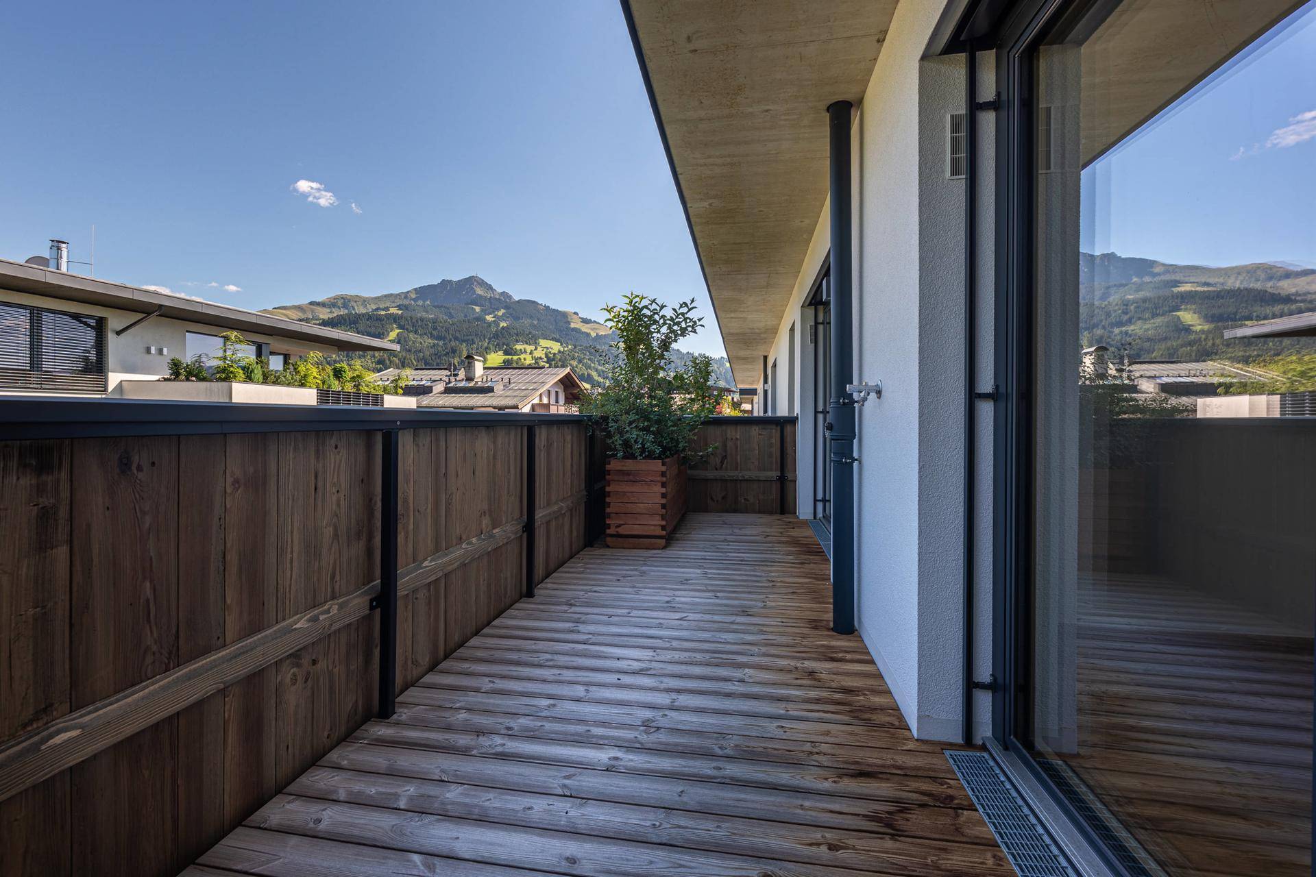 Langer Holzbalkon mit moderner Holzverkleidung und weitem Blick auf die Berge.