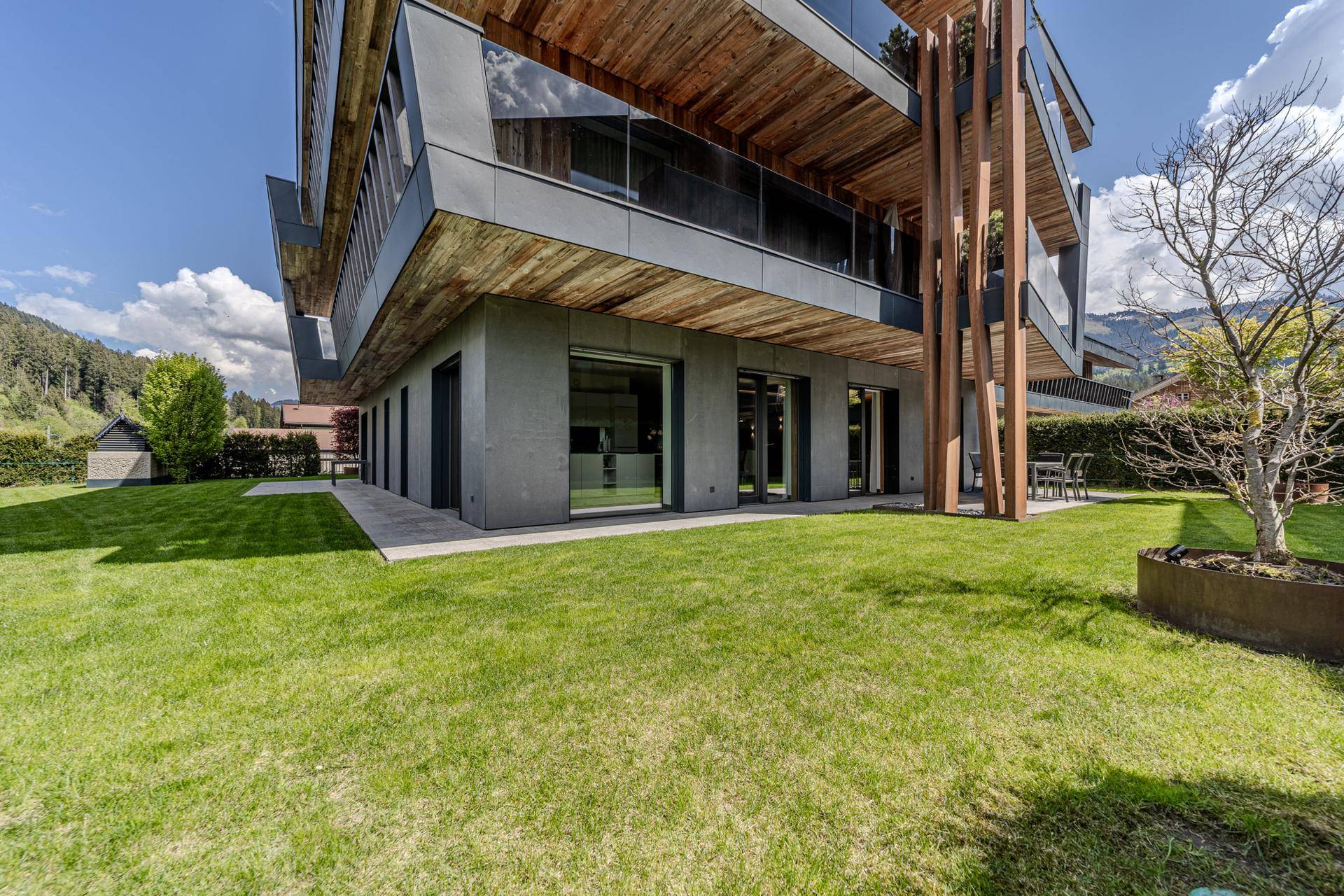Gepflegter Rasenbereich neben einem modernen Gebäude mit Holz- und Betonelementen.