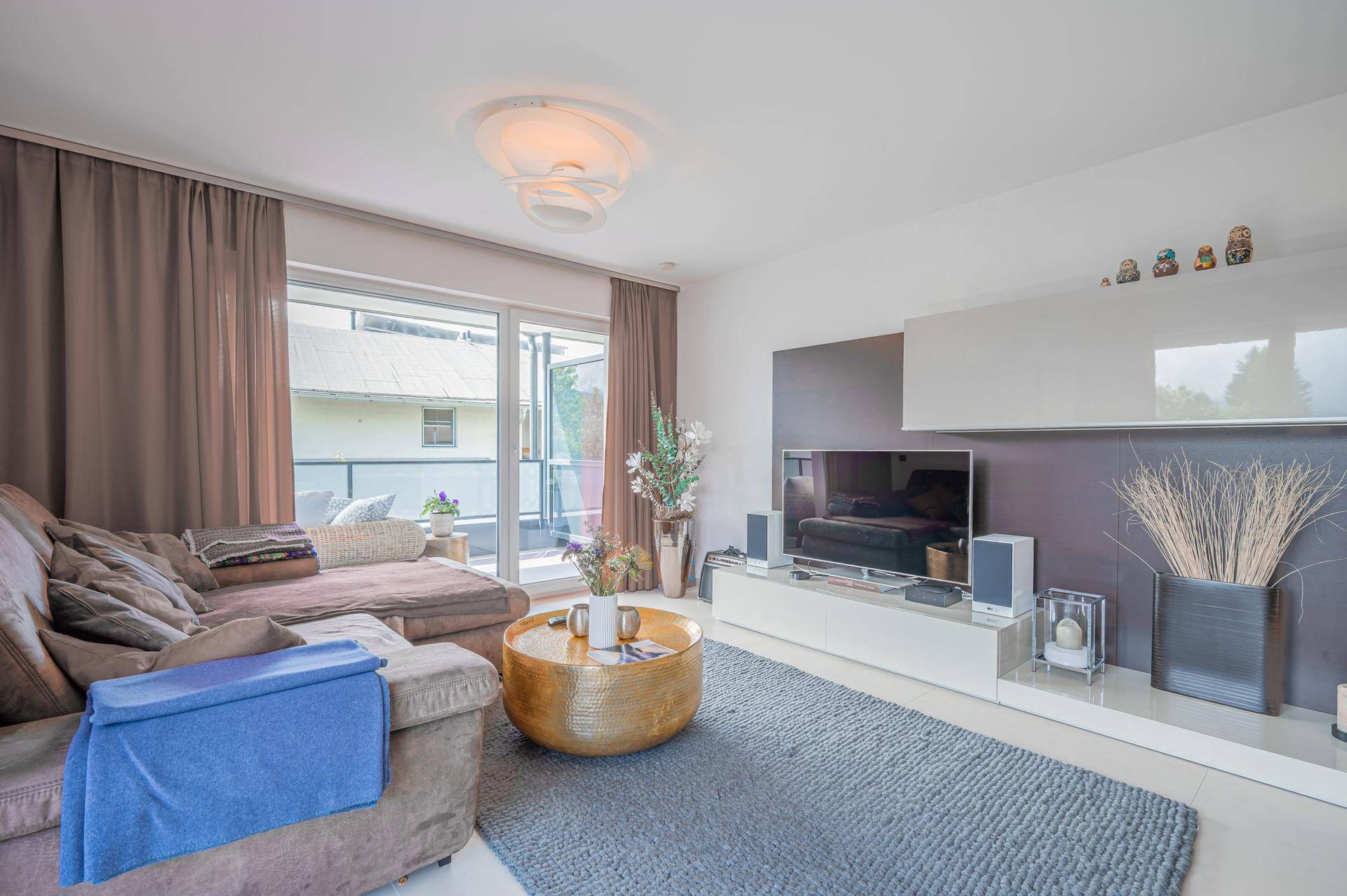 Modernes Wohnzimmer mit bequemer Couch, TV-Möbeln und direktem Zugang zum Außenbereich.