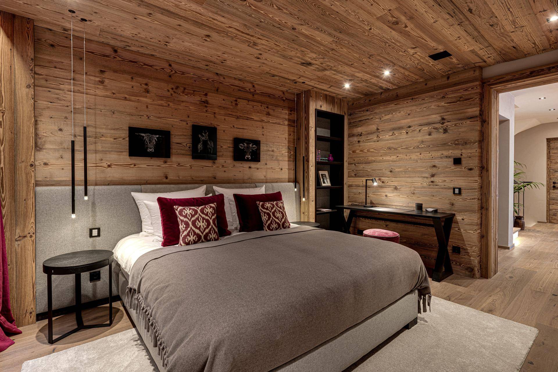 Gemütliches Schlafzimmer mit Holzwänden und -decke, modernem Bett und integriertem Schreibtischbereich.