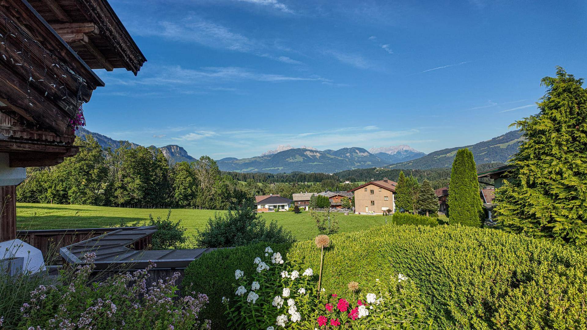 Malerischer Ausblick vom Balkon mit bunten Blumen auf die umliegende Landschaft und Berge.