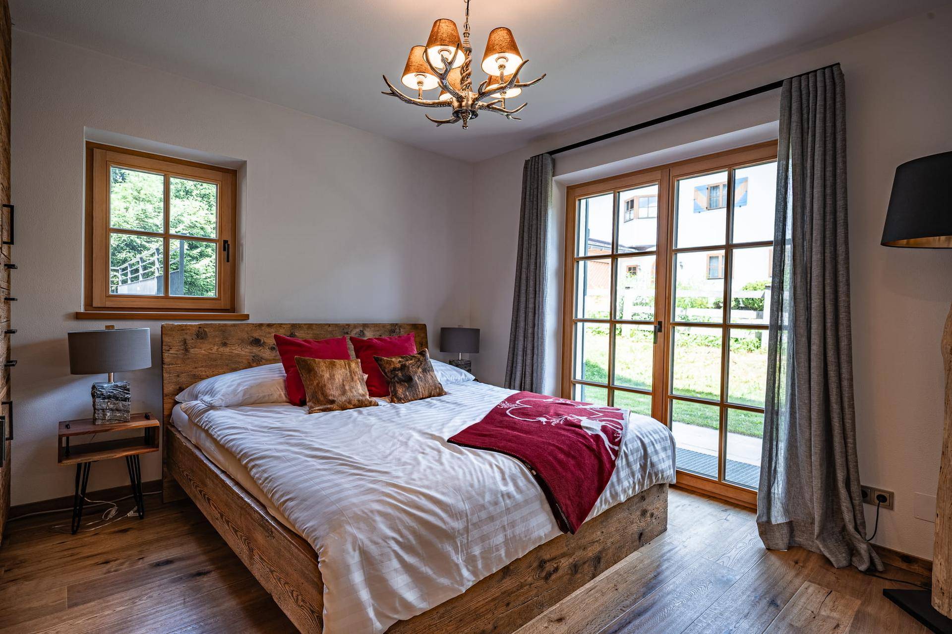 Helles Schlafzimmer mit Holzbett, Parkettboden und Zugang zum Außenbereich.