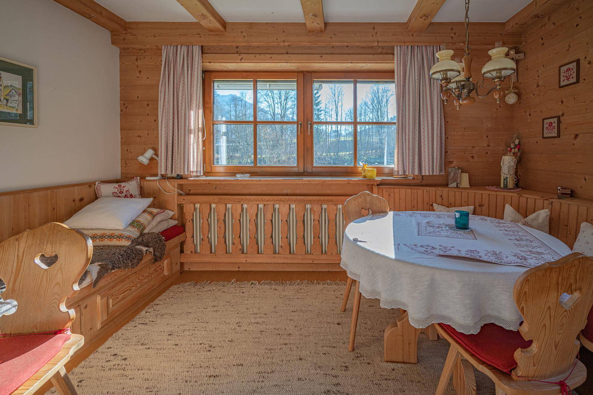 Gemütlicher Essbereich im alpinen Stil mit Holztäfelung, Sitzbank und Blick auf die Berge.