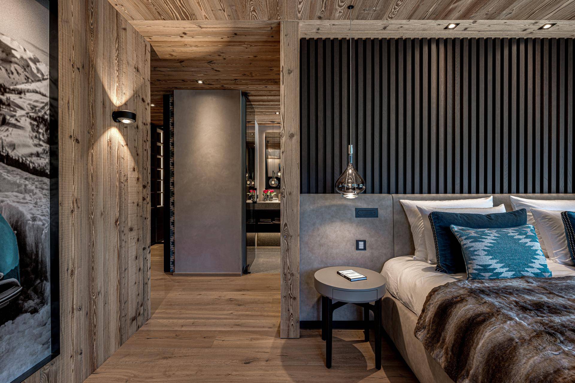 Elegantes Schlafzimmer mit Holzelementen und Blick auf ein modernes Badezimmer durch eine offene Tür.
