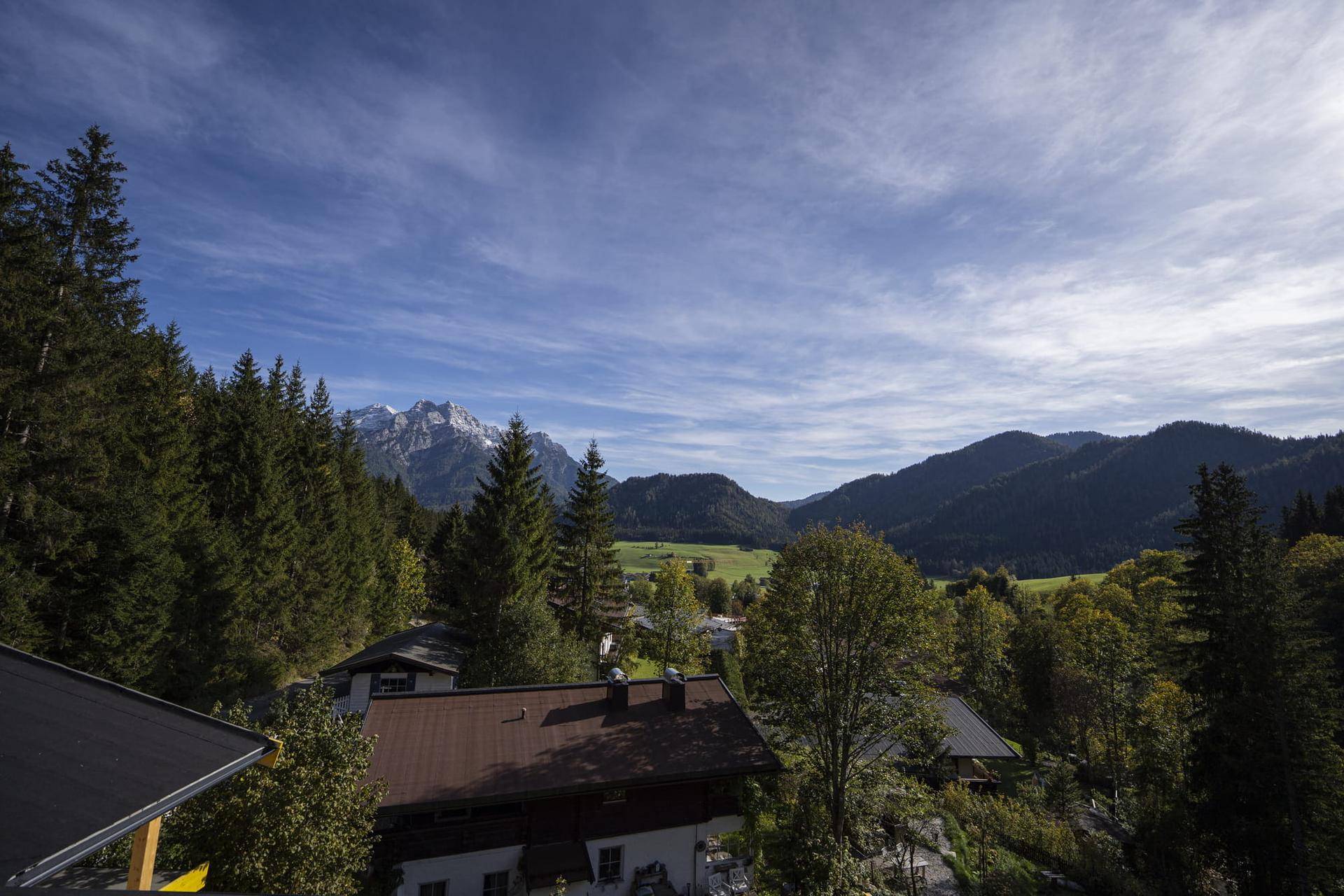 Panoramablick auf die umliegende Berglandschaft mit Wäldern und vereinzelten Häusern.